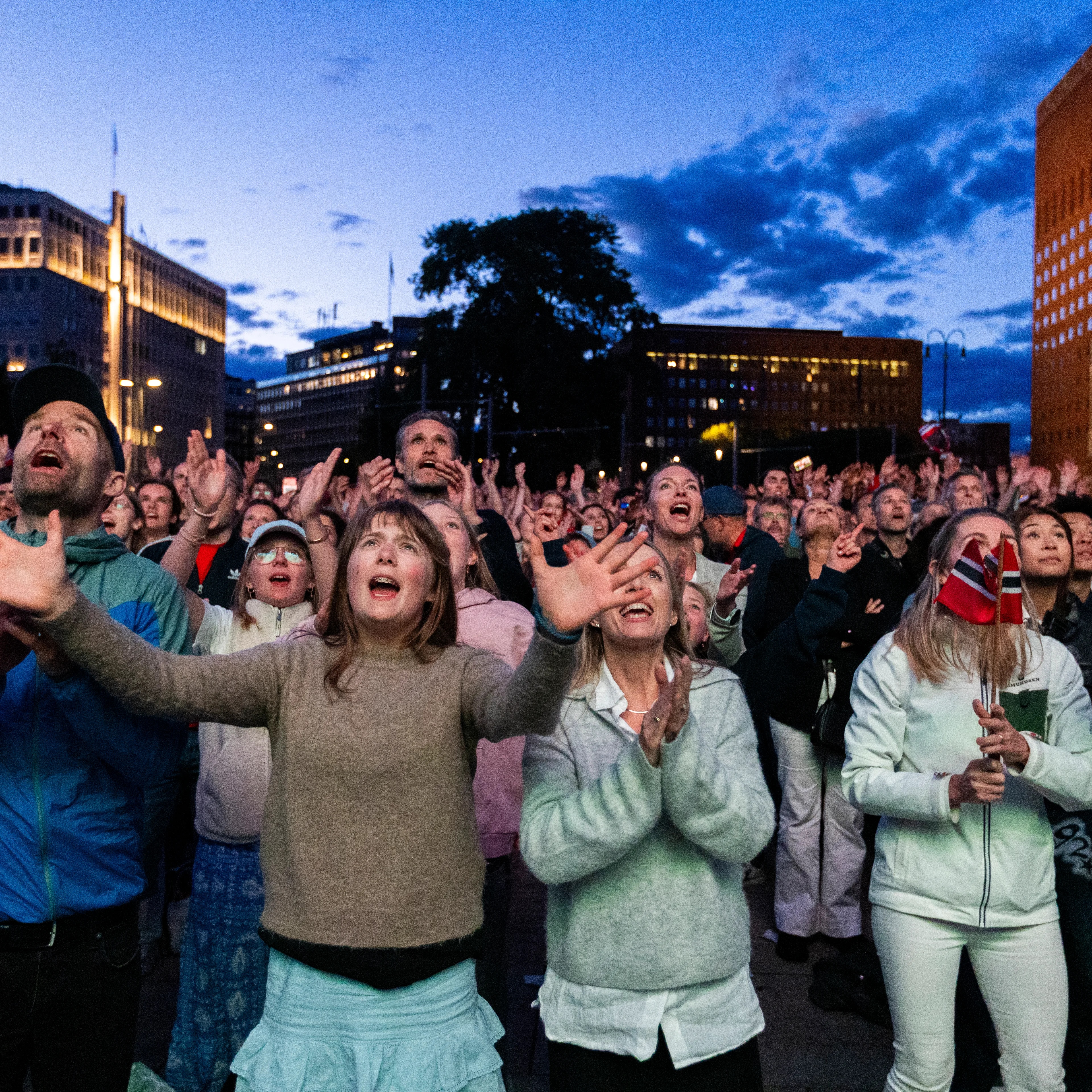 Folkemengde foran Rådhuset i Oslo jubler med oppstrakte hender.