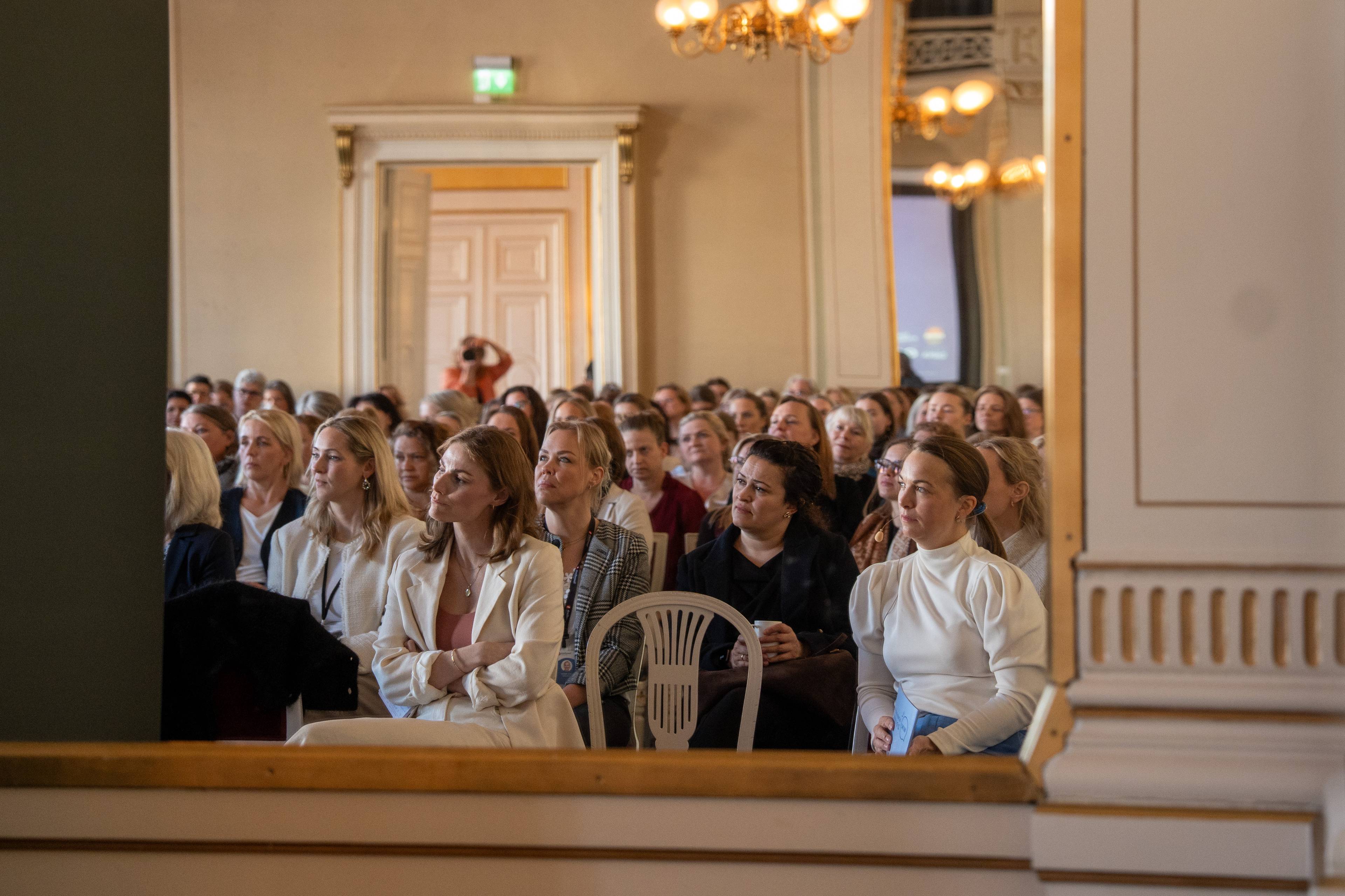 Mange kvinner sitter i en sal