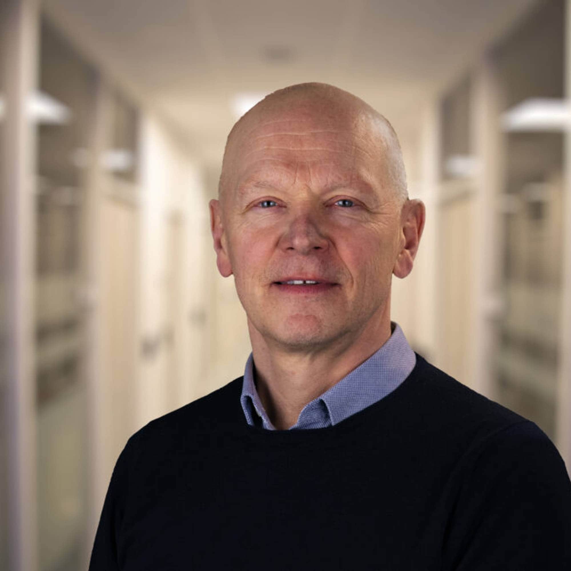 En mann står i en gang og ser i kamera