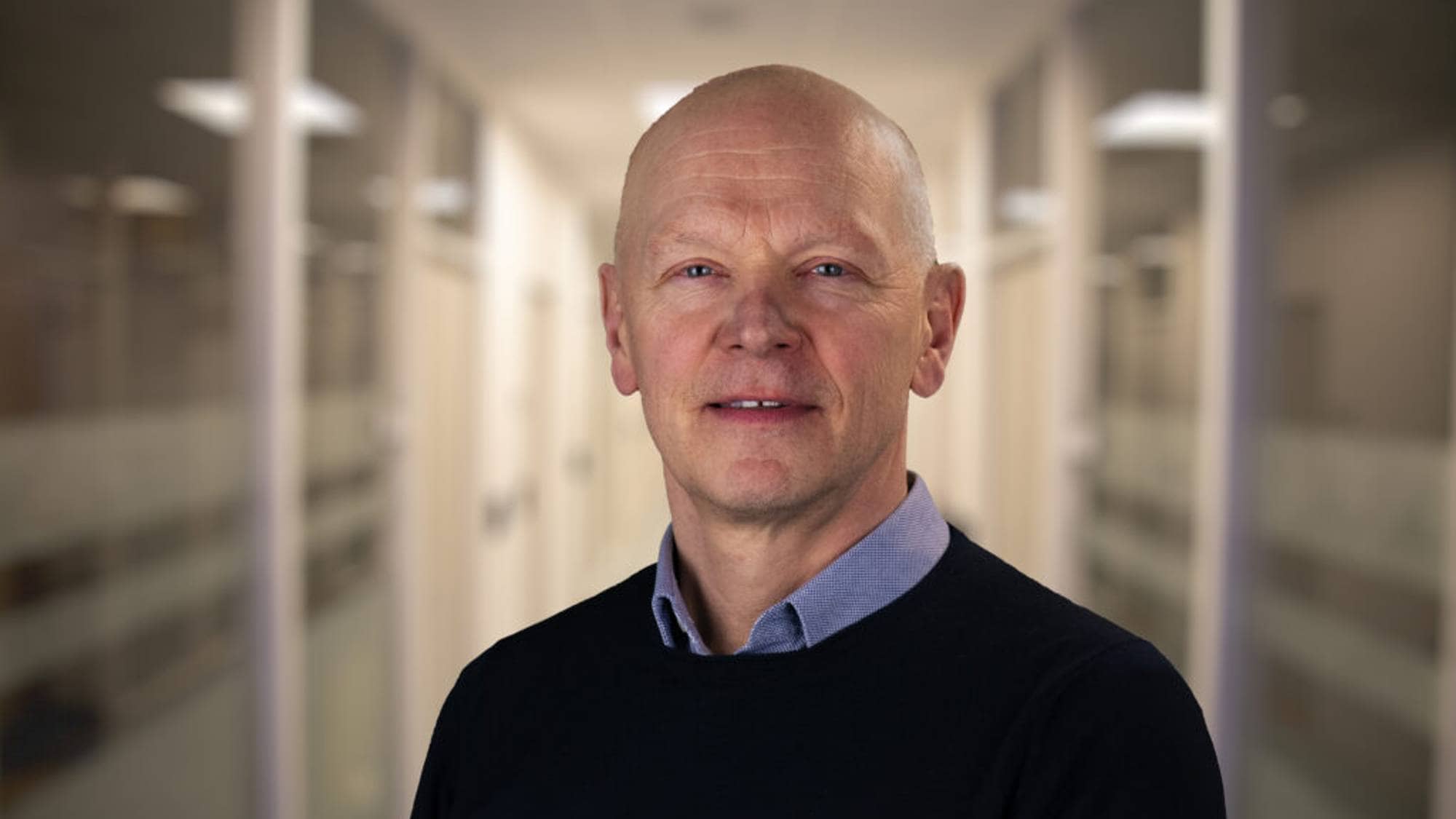 En mann står i en gang og ser i kamera