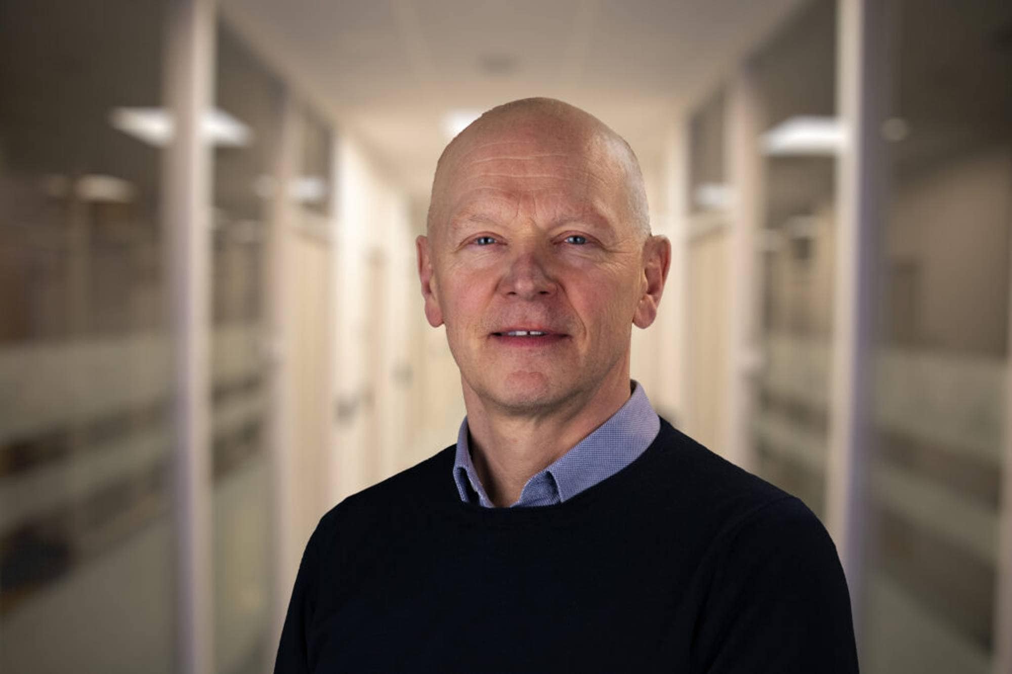 En mann står i en gang og ser i kamera