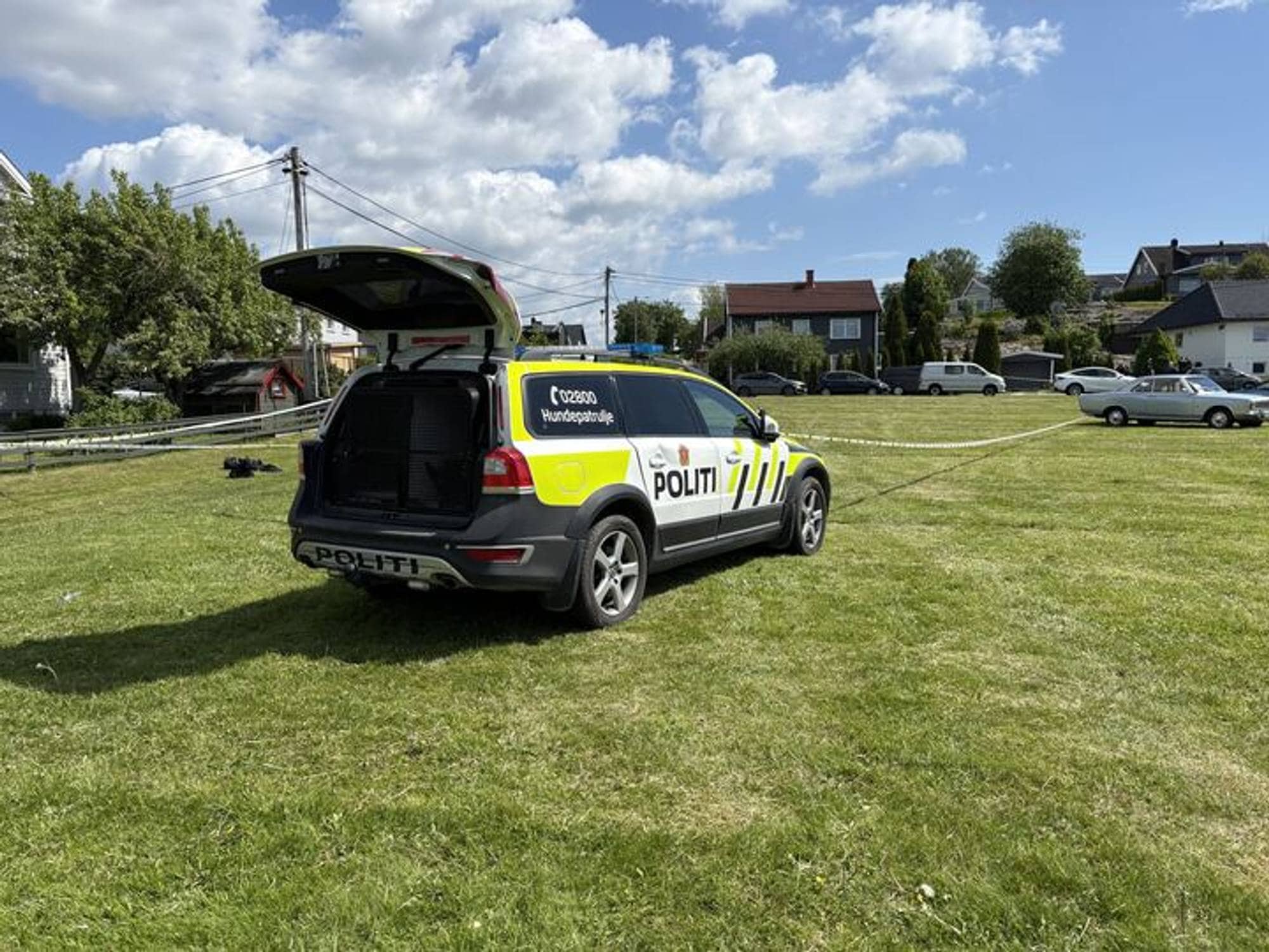 En politibil med åpen bakluke på en gressplen.