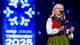 Lise Åserud / NTB En kvinne i bunad holder et blått hefte og snakker i en mikrofon. Bak henne er en stor, blå bakgrunn med et hvitt logo og teksten «COOP TRONDHEIM 2025». Bakgrunnen har også et blått lysshow. Kvinnen har briller og et skjerf rundt halsen. (Bildebeskrivelsen er laget av en KI-tjeneste)
