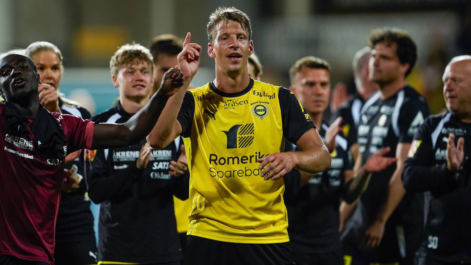 Lillestrøm-spillere jubler på banen etter en kamp. (Bildebeskrivelsen er laget av en KI-tjeneste)