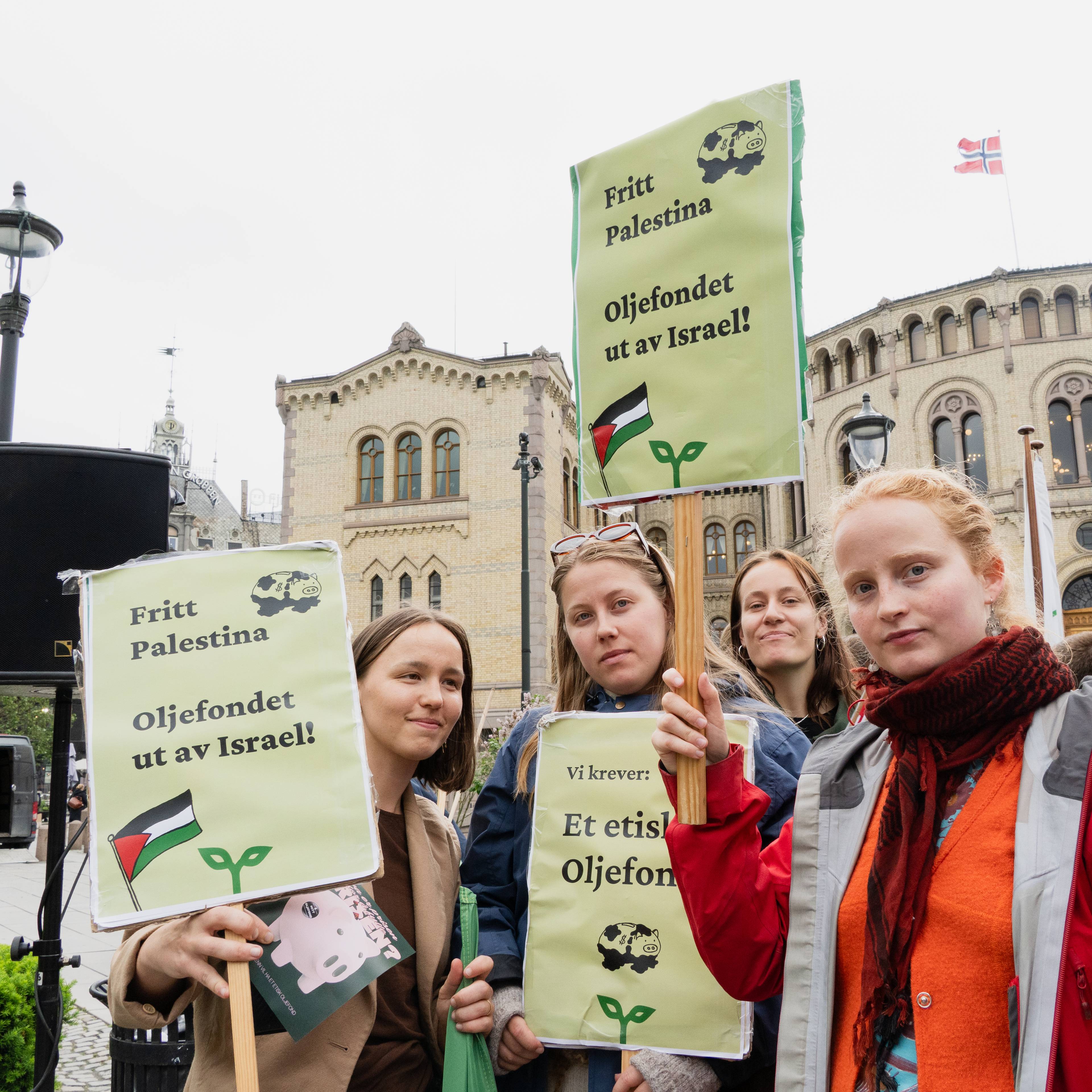 Fire unge damer står med skilt hvor det står slagord om oljefondet, med Stortinget i bakgrunnen