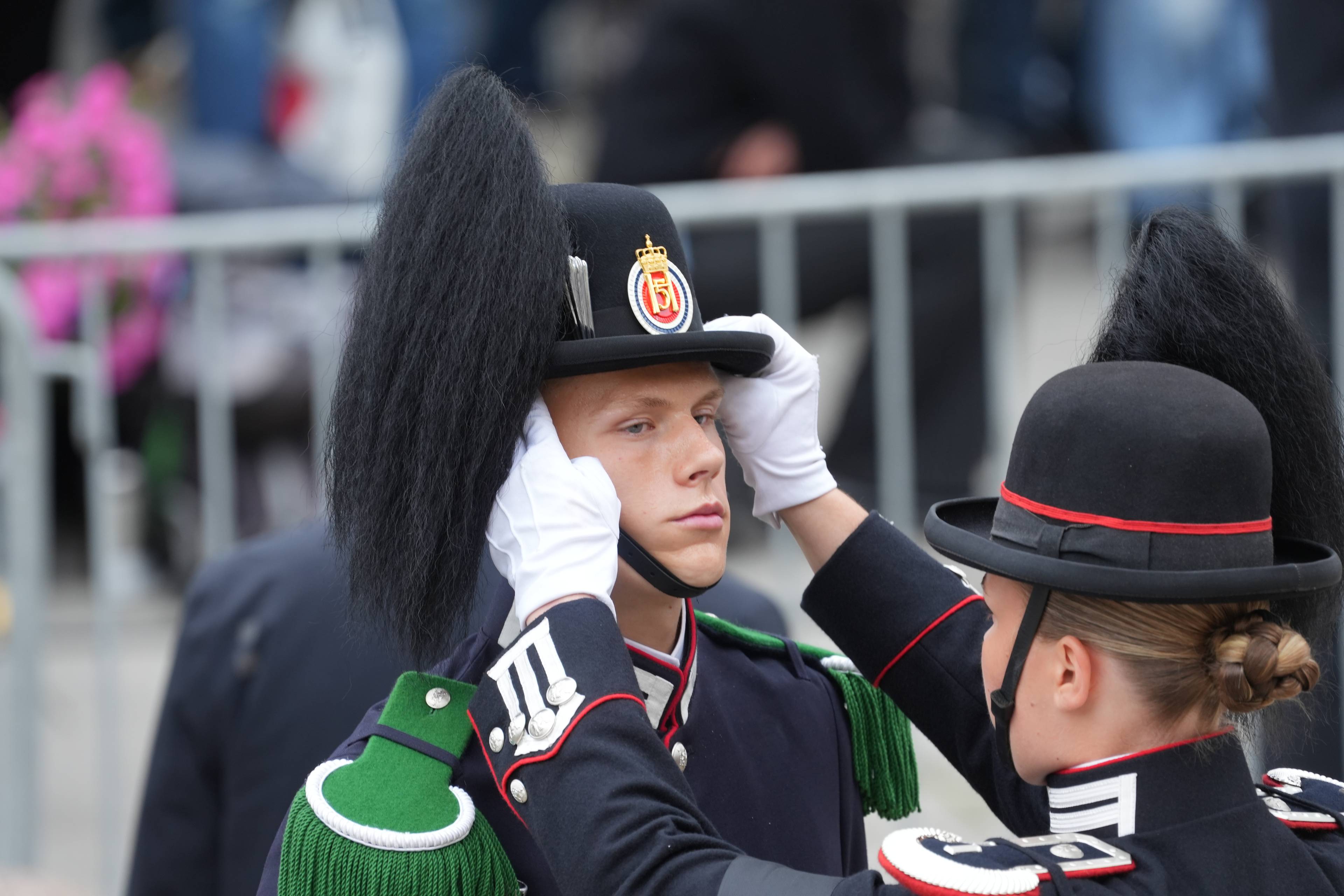 En garden soldat retter på hodeplagget til en annen gardist i uniform. (Bildebeskrivelsen er laget av en KI-tjeneste)