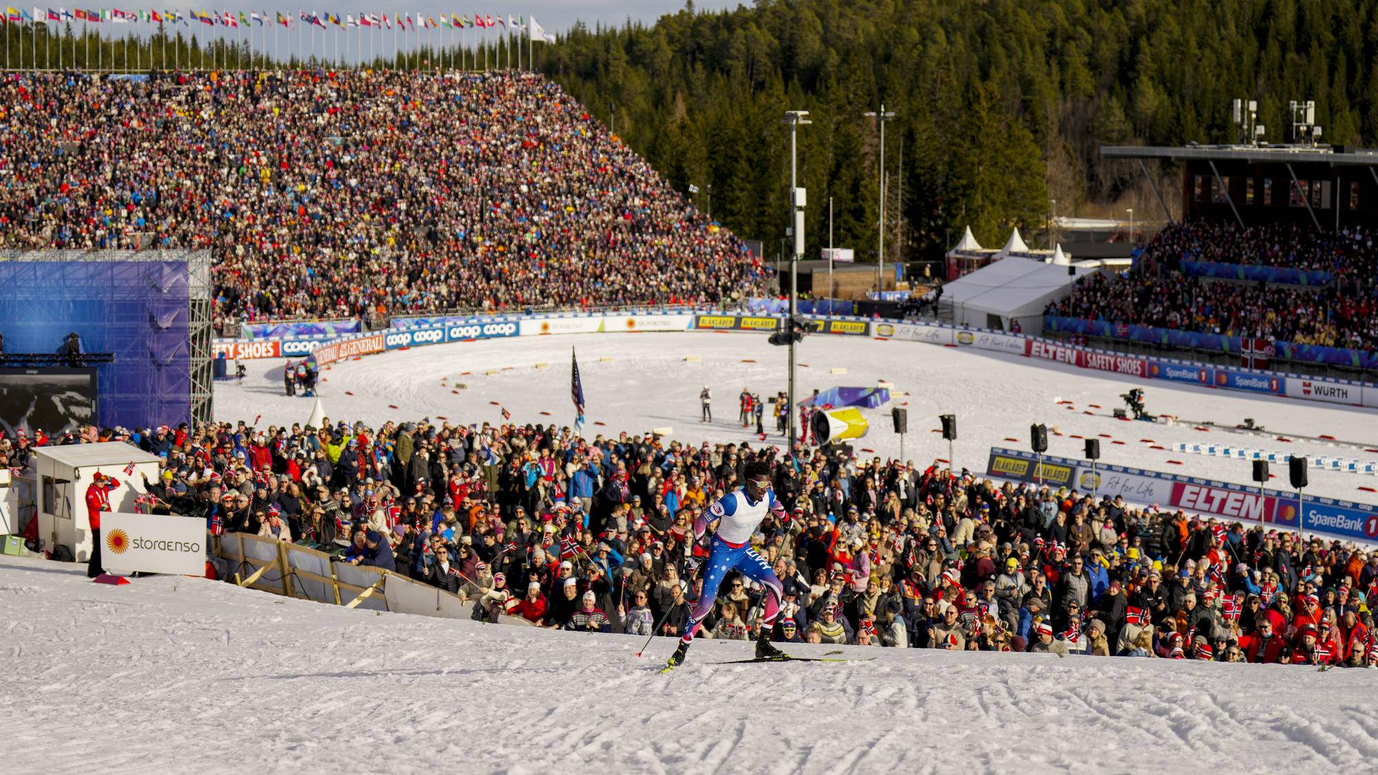 Langrennsløper i Holmenkollen med fullsatte tribuner i bakgrunnen. (Bildebeskrivelsen er laget av en KI-tjeneste)