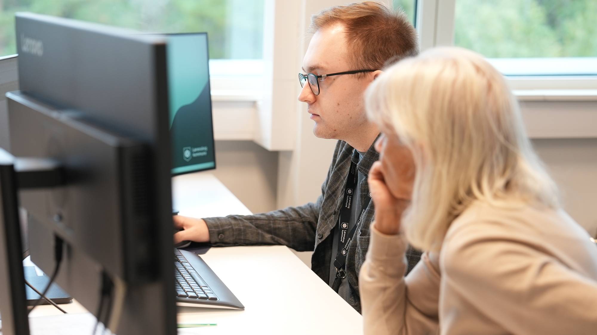 En mann med briller og en dame med hvitt hår ser inn i dataskjerm