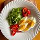 Julie Haugen Egge / NRK Et hvitt fat med egg, ruccolasalat og paprika på.