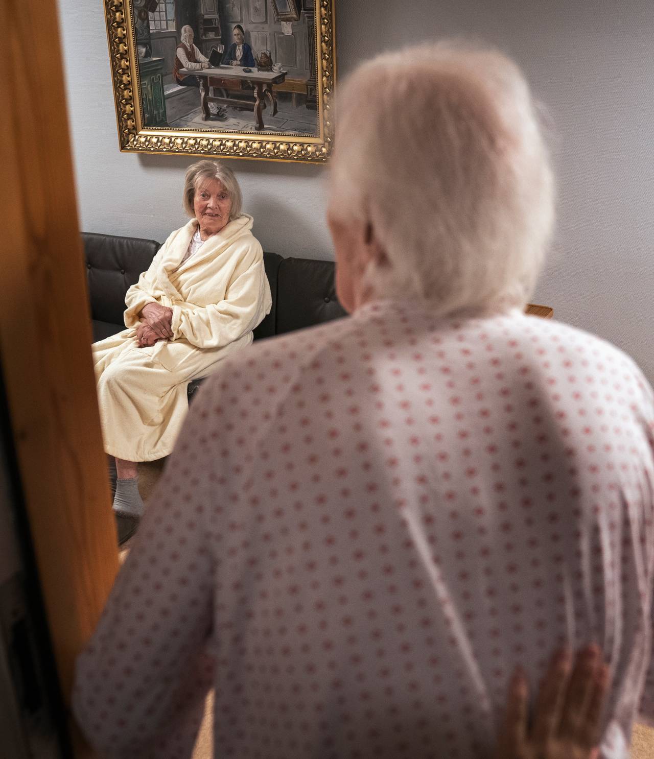 Birger står i døråpningen og møter blikket til Randi, som sitter i sofaen i gangen utenfor.