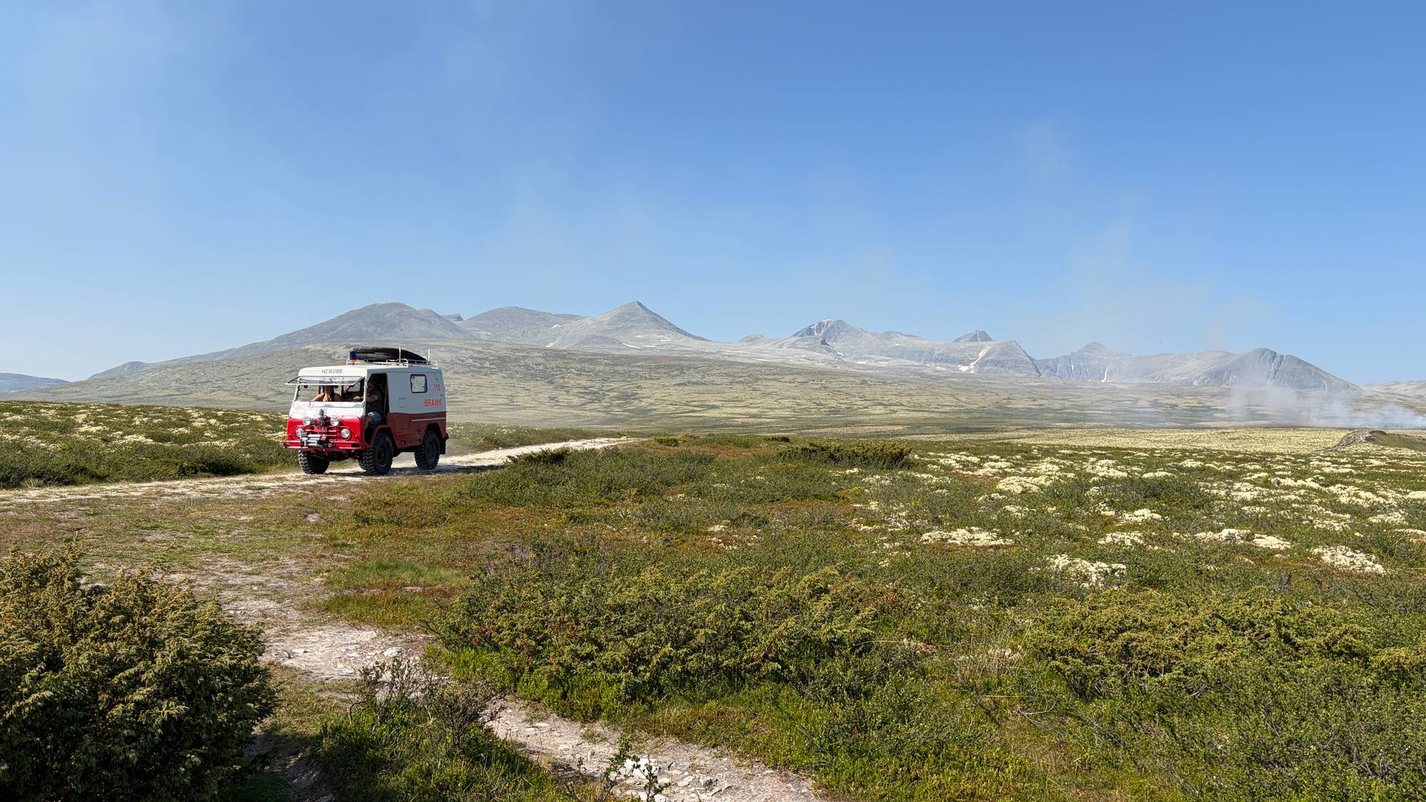 en gammel brannbil foran en lyngbrann