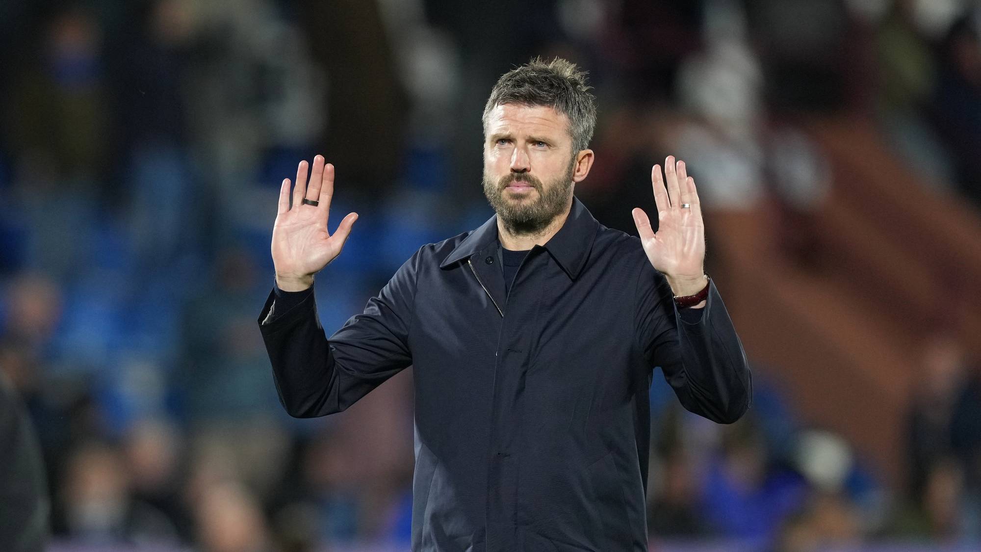 Michael Carrick står med hendene hevet foran seg på en fotballstadion. (Bildebeskrivelsen er laget av en KI-tjeneste)