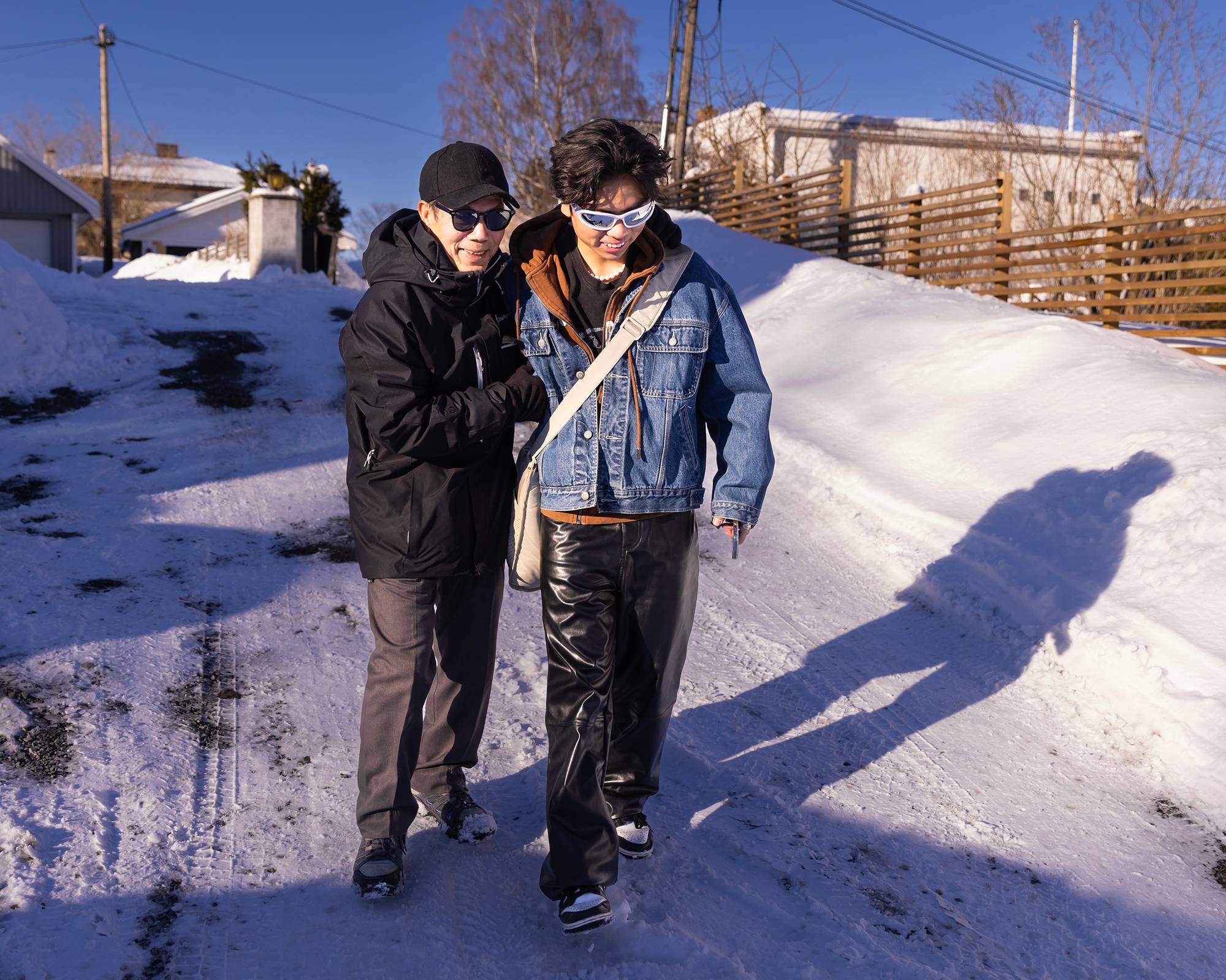 Bestefar Hinh og Filip går langs en snøkledd vei i Asker. Hinh holder i armen til Filip over de glatte partiene. Hinh har på seg caps, solbriller og en sporty jakke. Filip har på seg solbriller, dongerijakke og skinnbukser. 