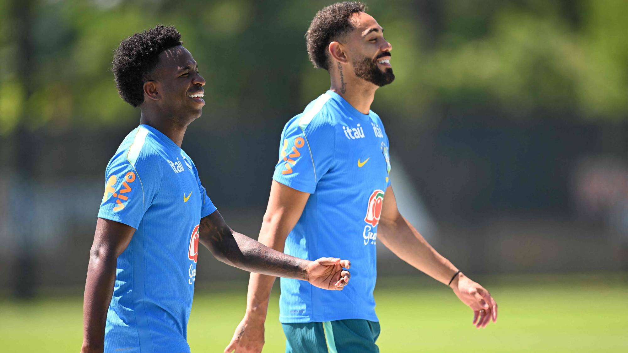 Vinícius Júnior og en lagkamerat i Brasils landslagsdrakter går smilende over en fotballbane. (Bildebeskrivelsen er laget av en KI-tjeneste)