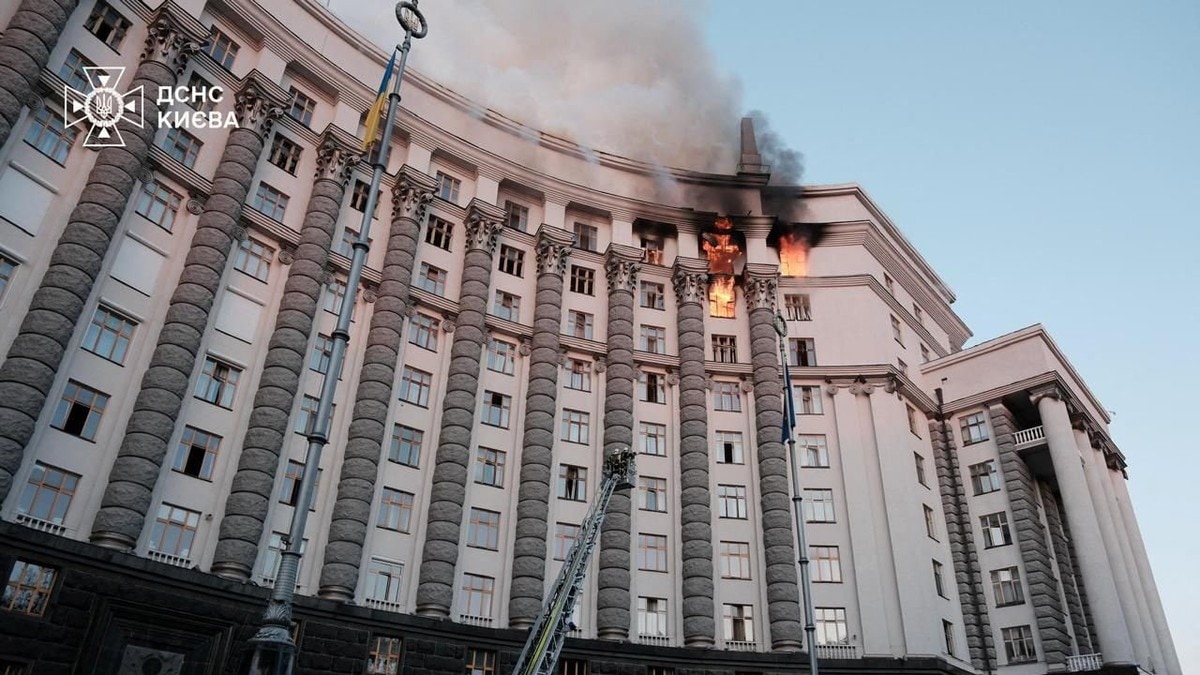 Regjeringsbygget i Kyiv. En svakt avrundet bygning, bildet tatt nedenfra og opp mot brann i flere kontorer.