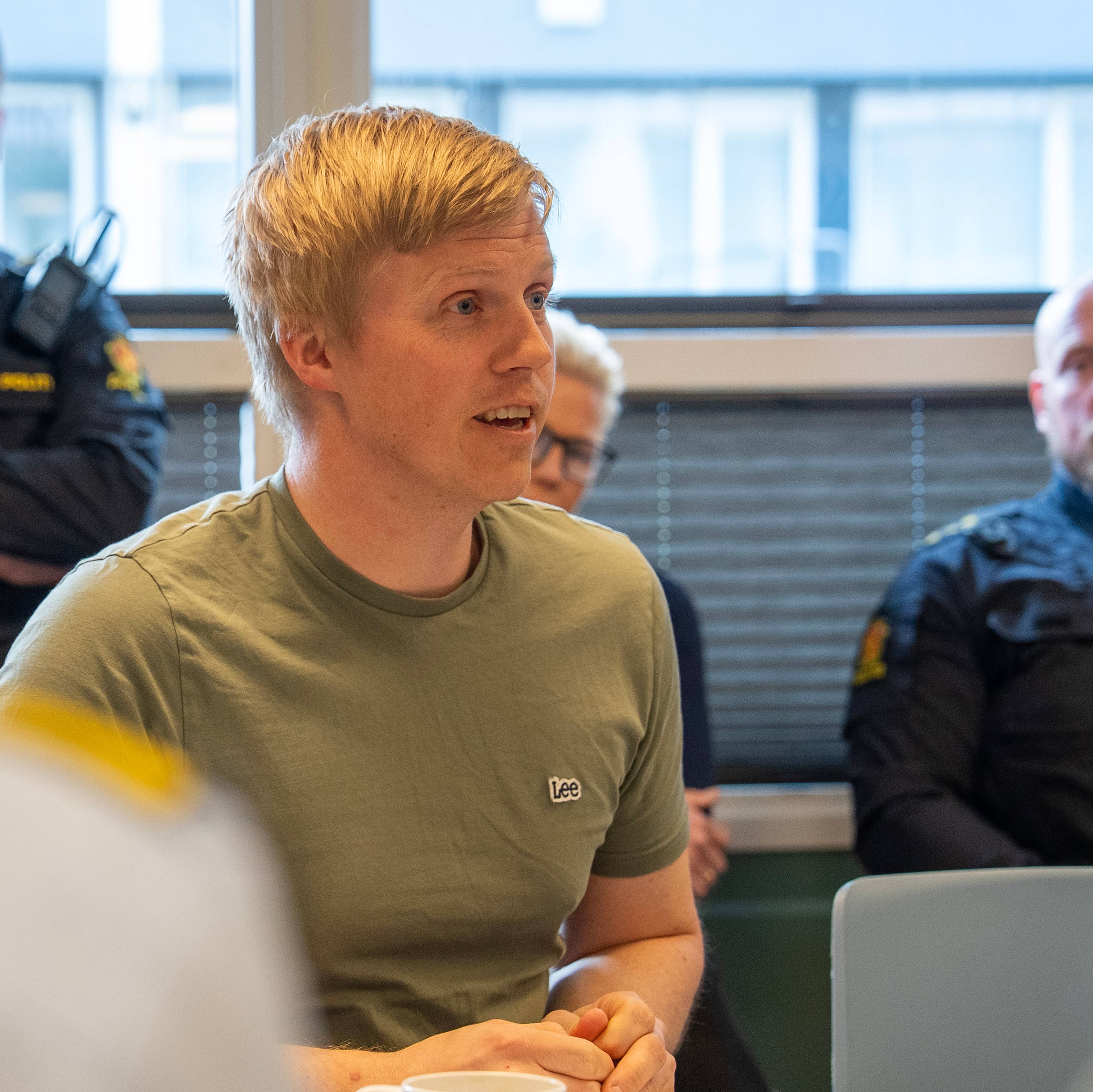 ung blond, kort klippet mann i grønn t-skjorte, ser til høyre i bildet