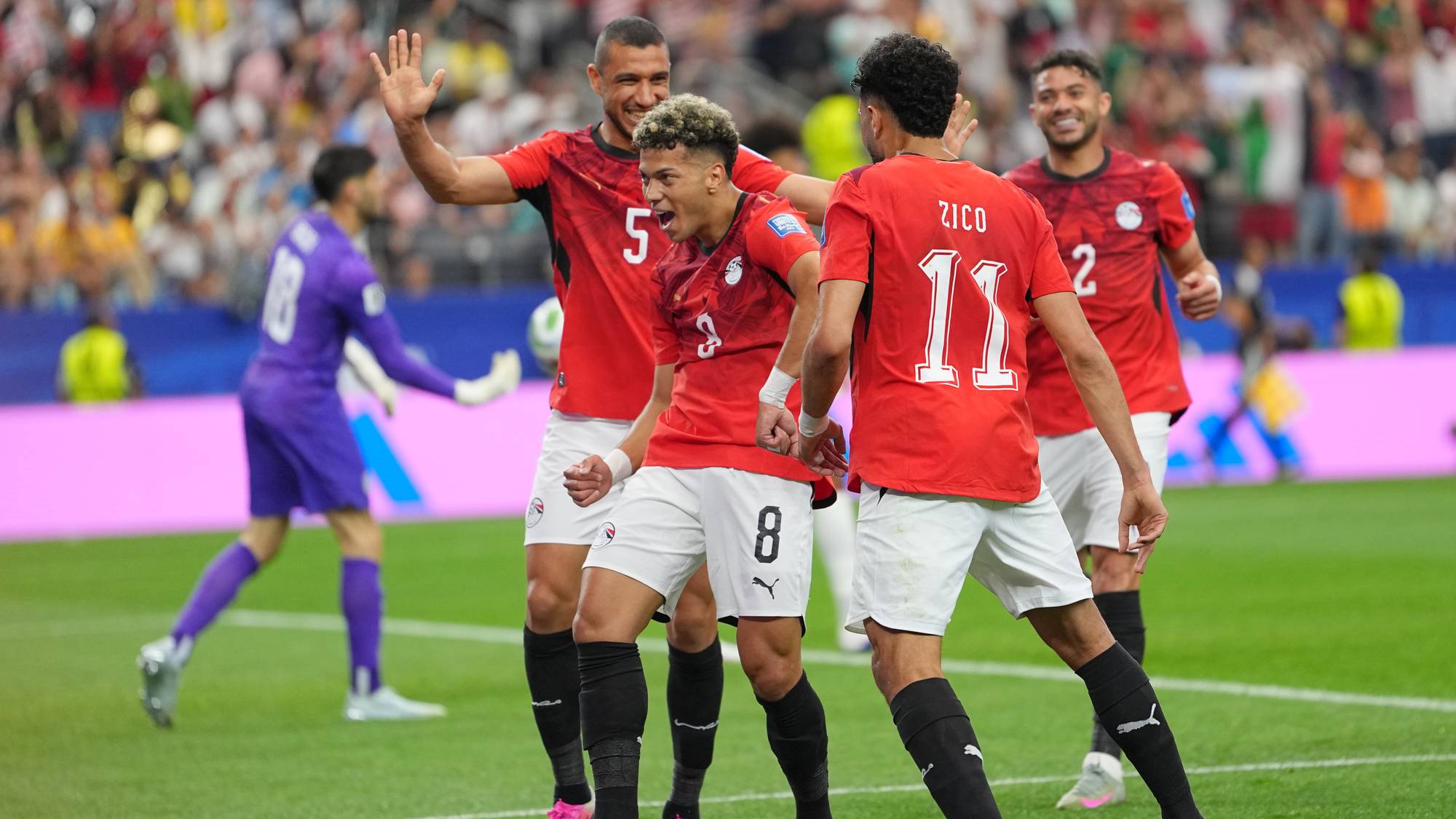 Fotballspillere på Egypts landslag feirer mål på banen. Bakgrunnen viser tribunene og en motspiller. (Bildebeskrivelsen er laget av en KI-tjeneste)