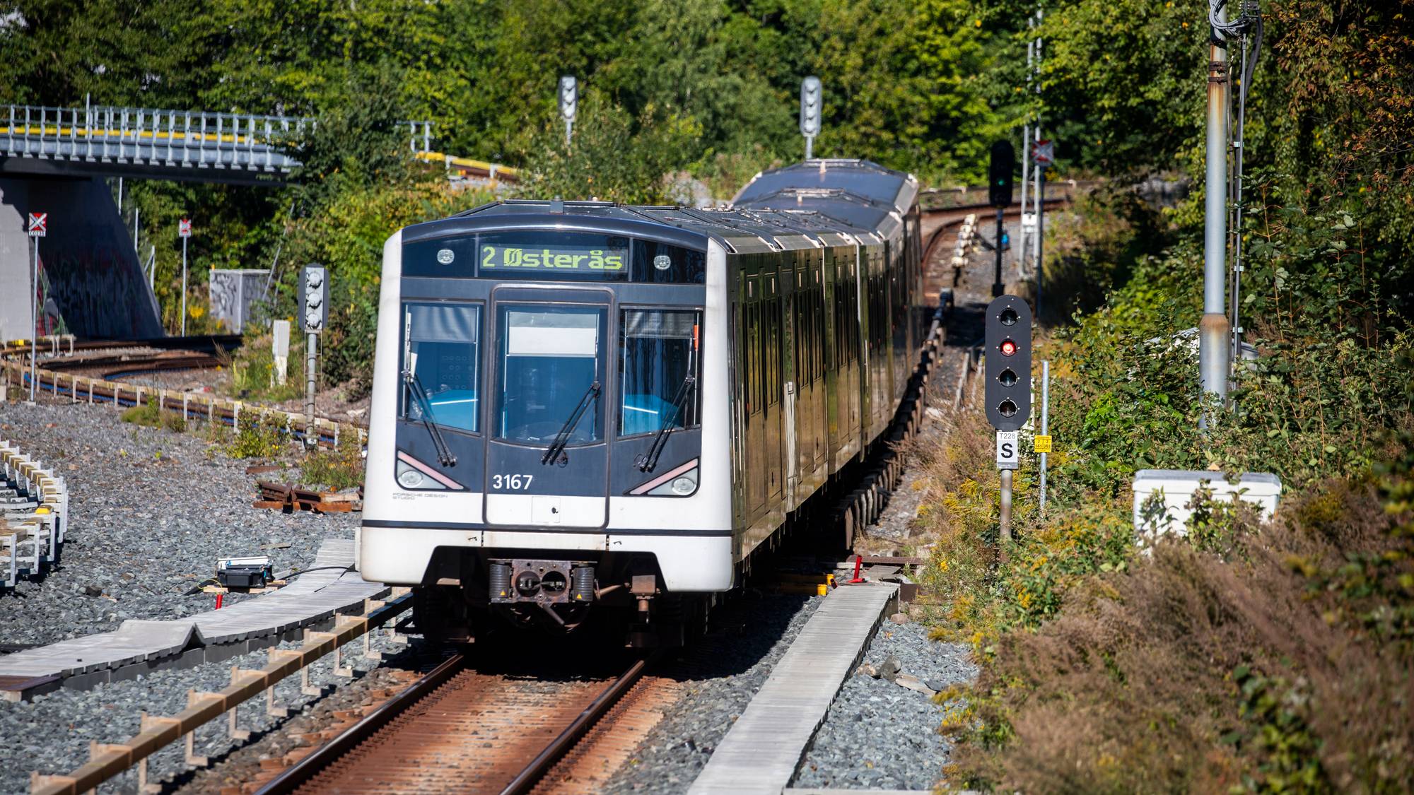 T-banevogn på vei mot Østerås kjører på skinnene i et skogkledd landskap. (Bildebeskrivelsen er laget av en KI-tjeneste)