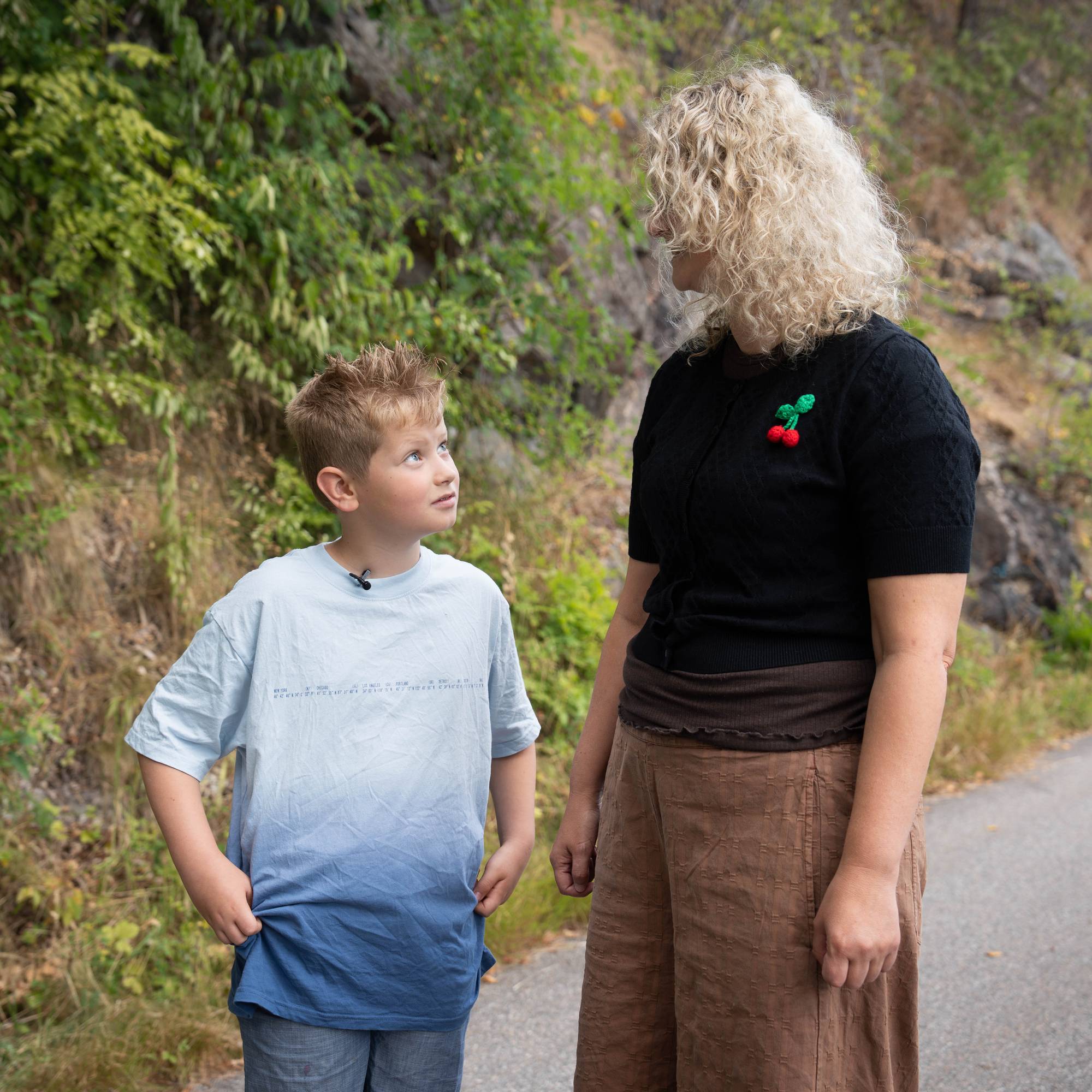 en mann og en gutt som går på en sti med trær i bakgrunnen (Bildebeskrivelsen er laget av en KI-tjeneste)