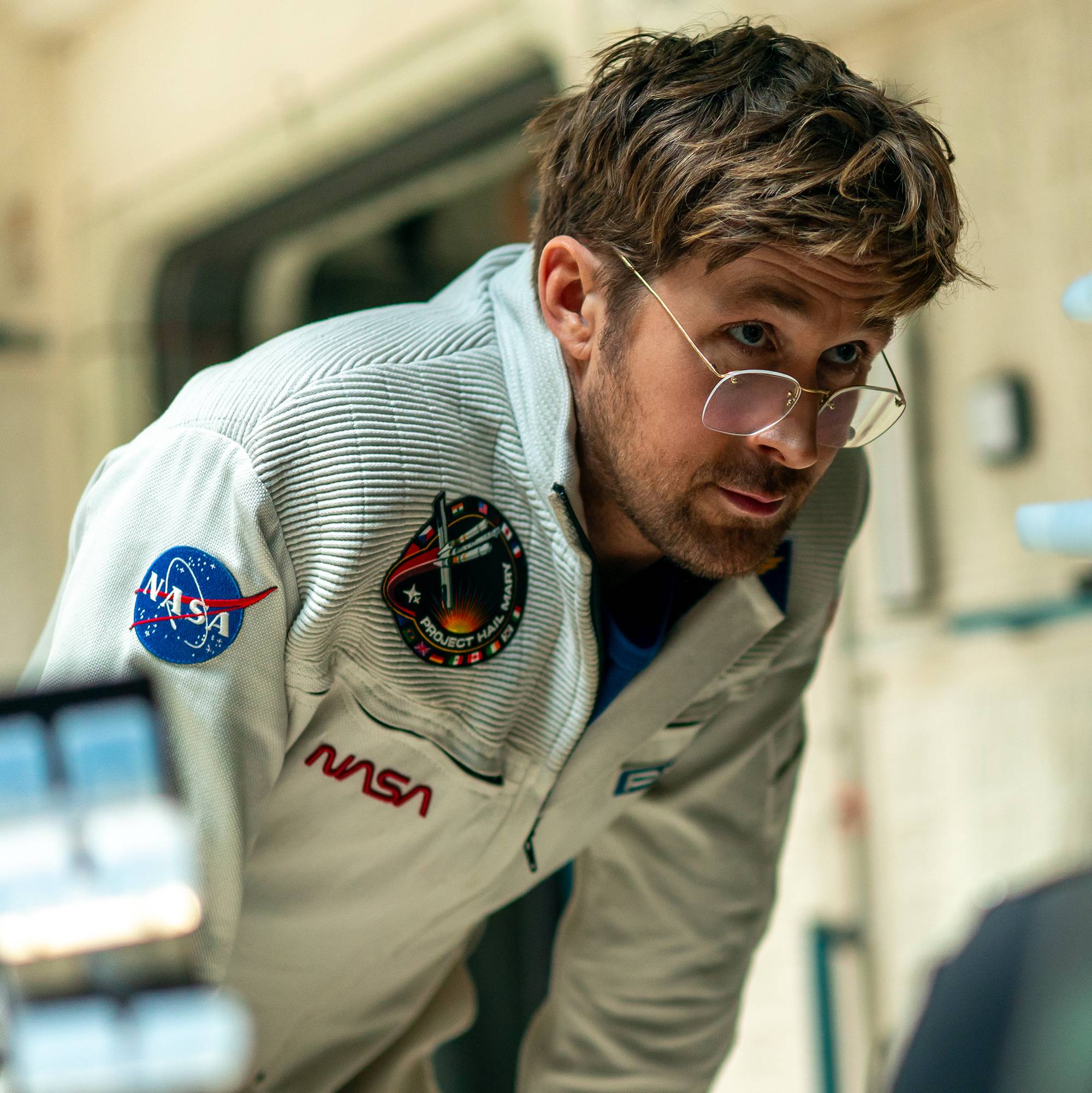 En mann i NASA-uniform står bøyd fremover.
