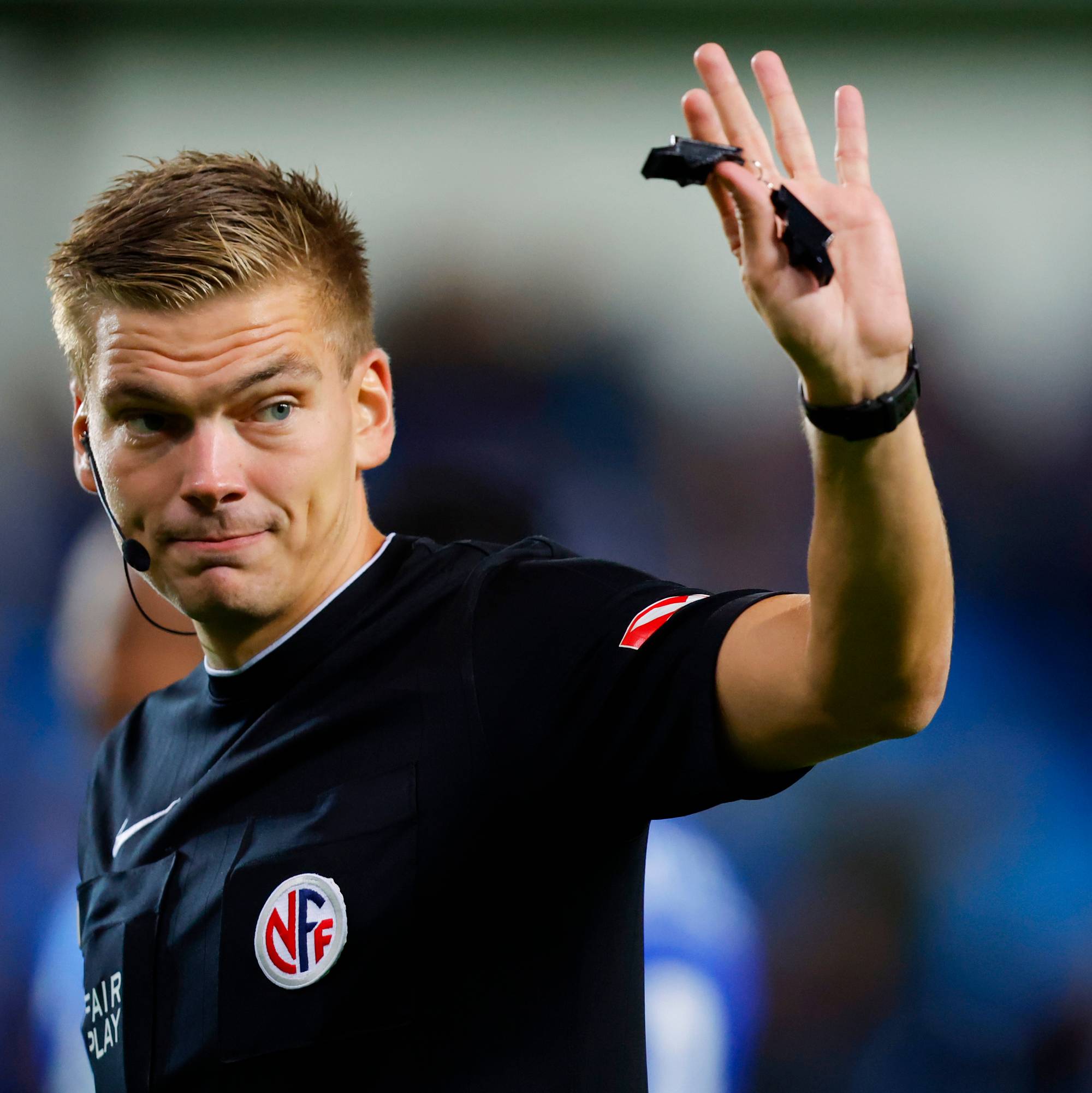 Fotballdommer holder opp en fløyte under en kamp. (Bildebeskrivelsen er laget av en KI-tjeneste)
