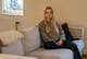 Helena Ringheim / NRK En person sitter på en beige sofa i et rom med lys vegg. Det er en lampe ved vinduet og et radiator i bakgrunnen. Personen har langt, lyst hår og iført en grå genser og mørkeblå bukser. Det ligger en myk, hvit pute på sofaen ved siden av.