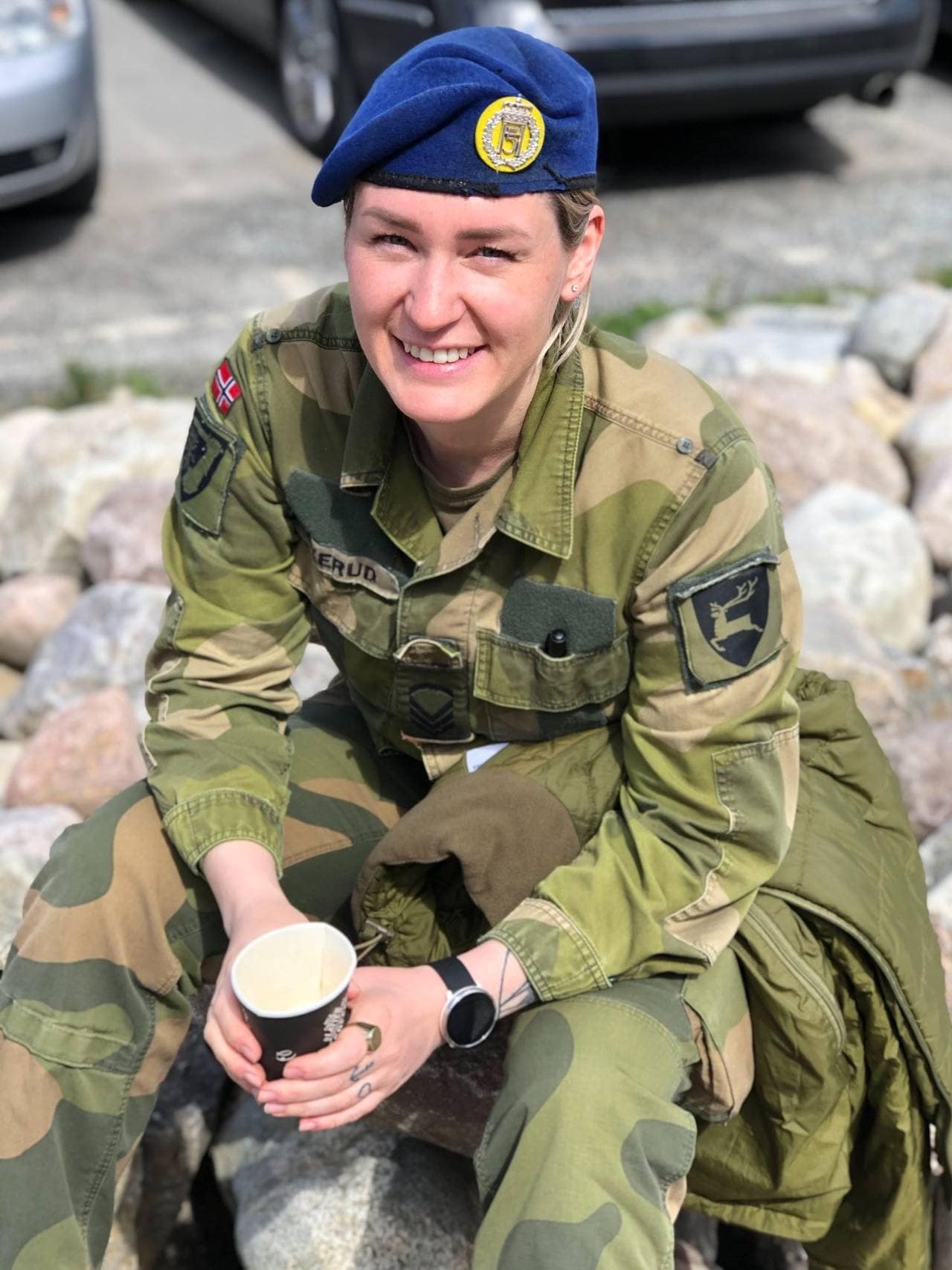 Kristine Solhaug sitter på en stein me den kaffekopp, iført uniform