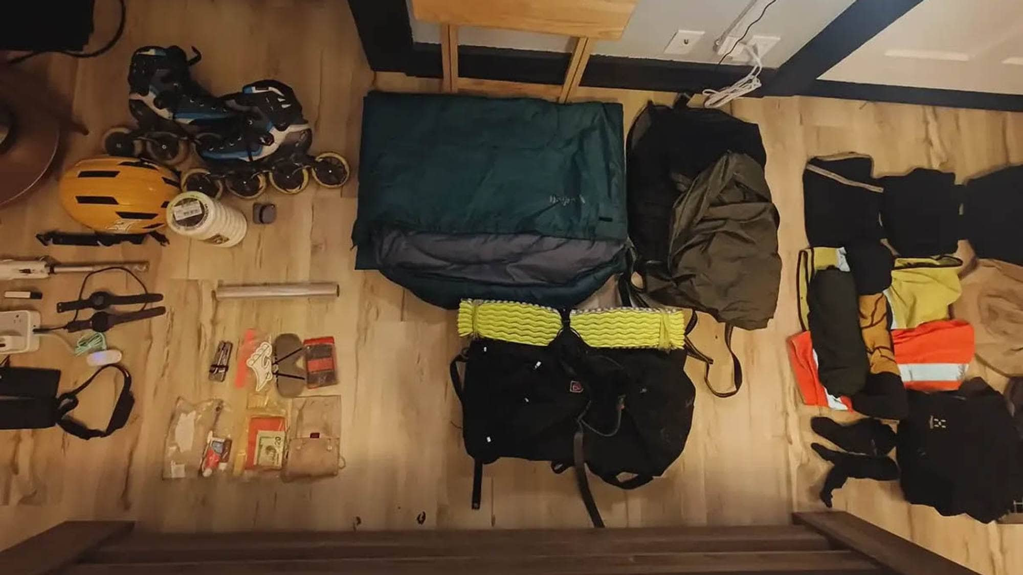 To føtter balanserer på en sengekant. På gulvet er en sekk og en del utstyr, som sovepose og telt, i tillegg til hjelm og rulleskøyter.