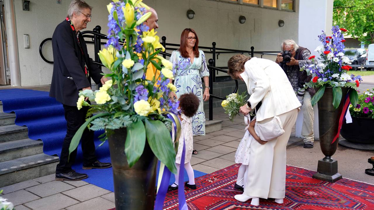 Et av barna til Lars Lerin klemmer dronning Sonja rundt benet