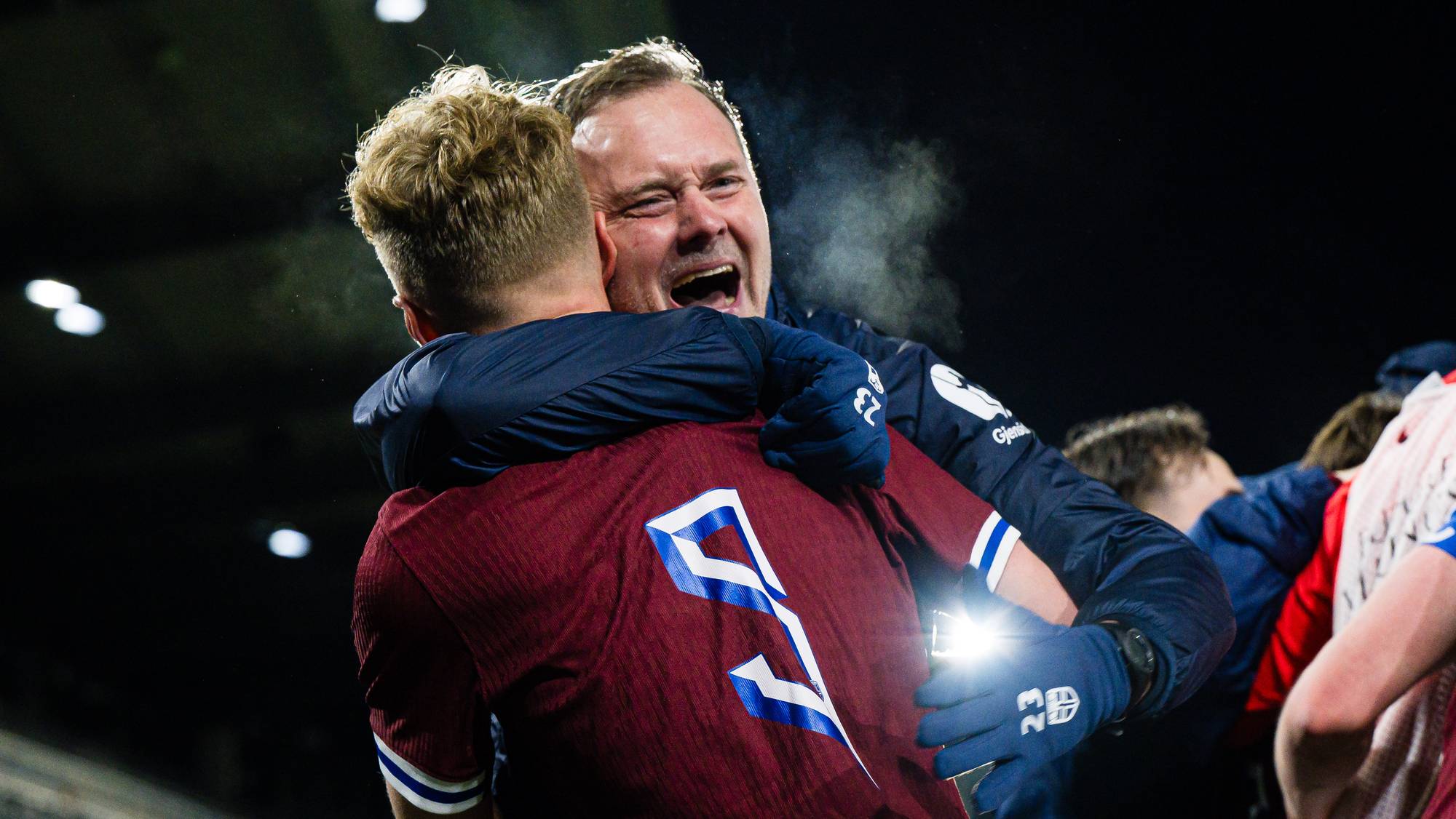 En fotballspiller og en trener omfavner hverandre på banen etter en kamp. (Bildebeskrivelsen er laget av en KI-tjeneste)