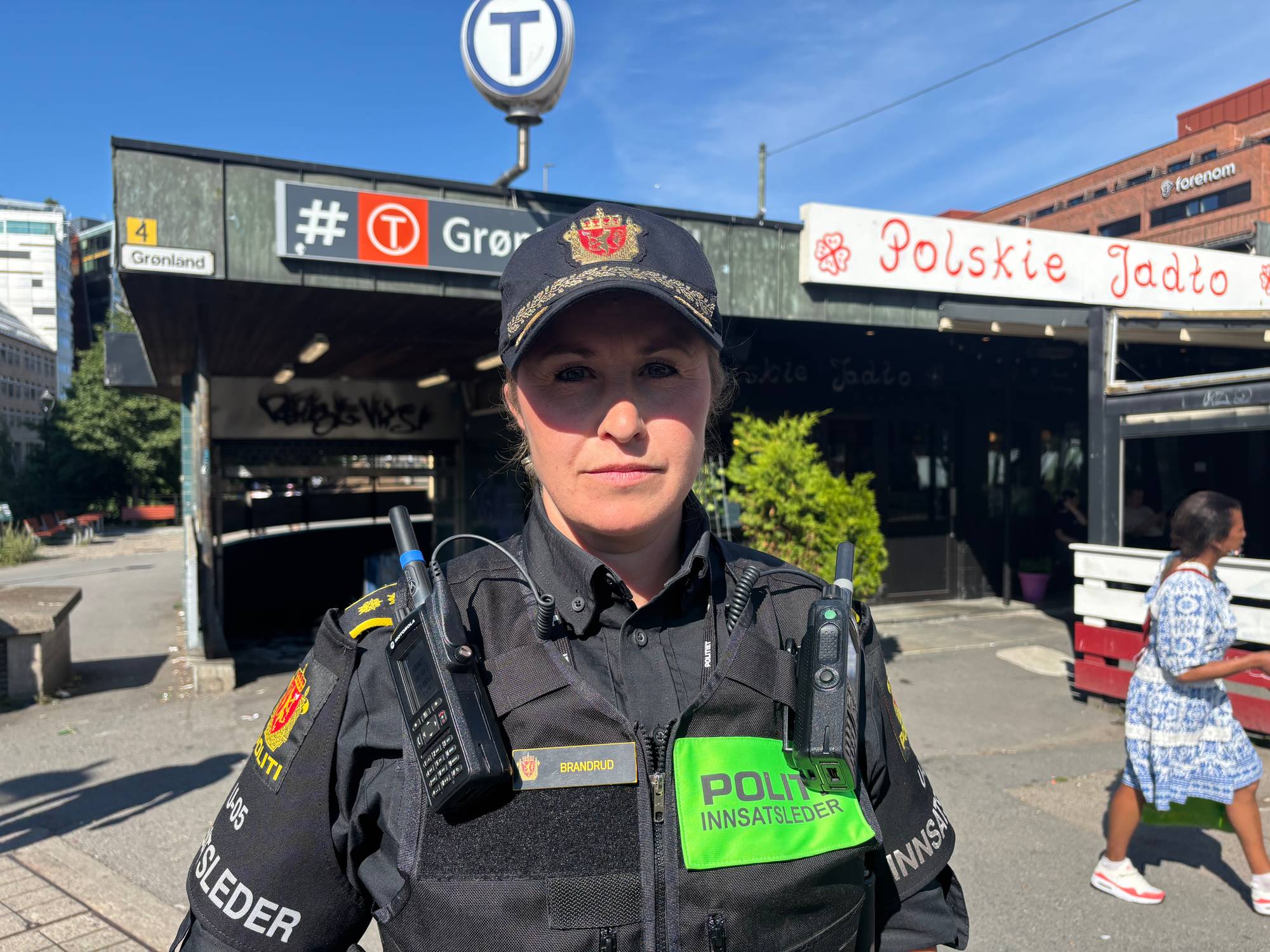 En kvinnelig politibetjent står foran en av inngangene til Grønland T-banestasjon.