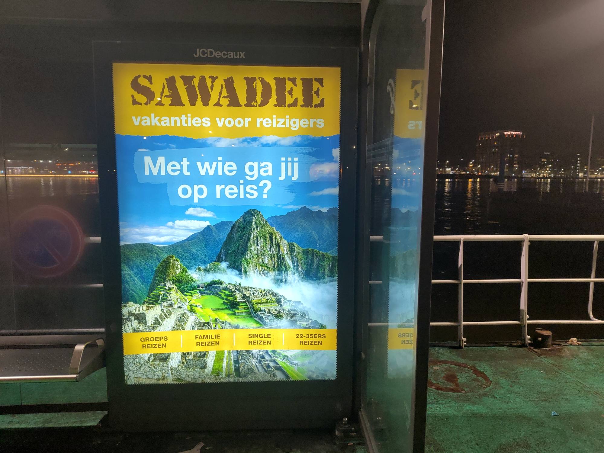 Bilde av en reklameplakat som viser olditdsbyen Machu Pichu. I bakgrunnen synes en mørklagt by.