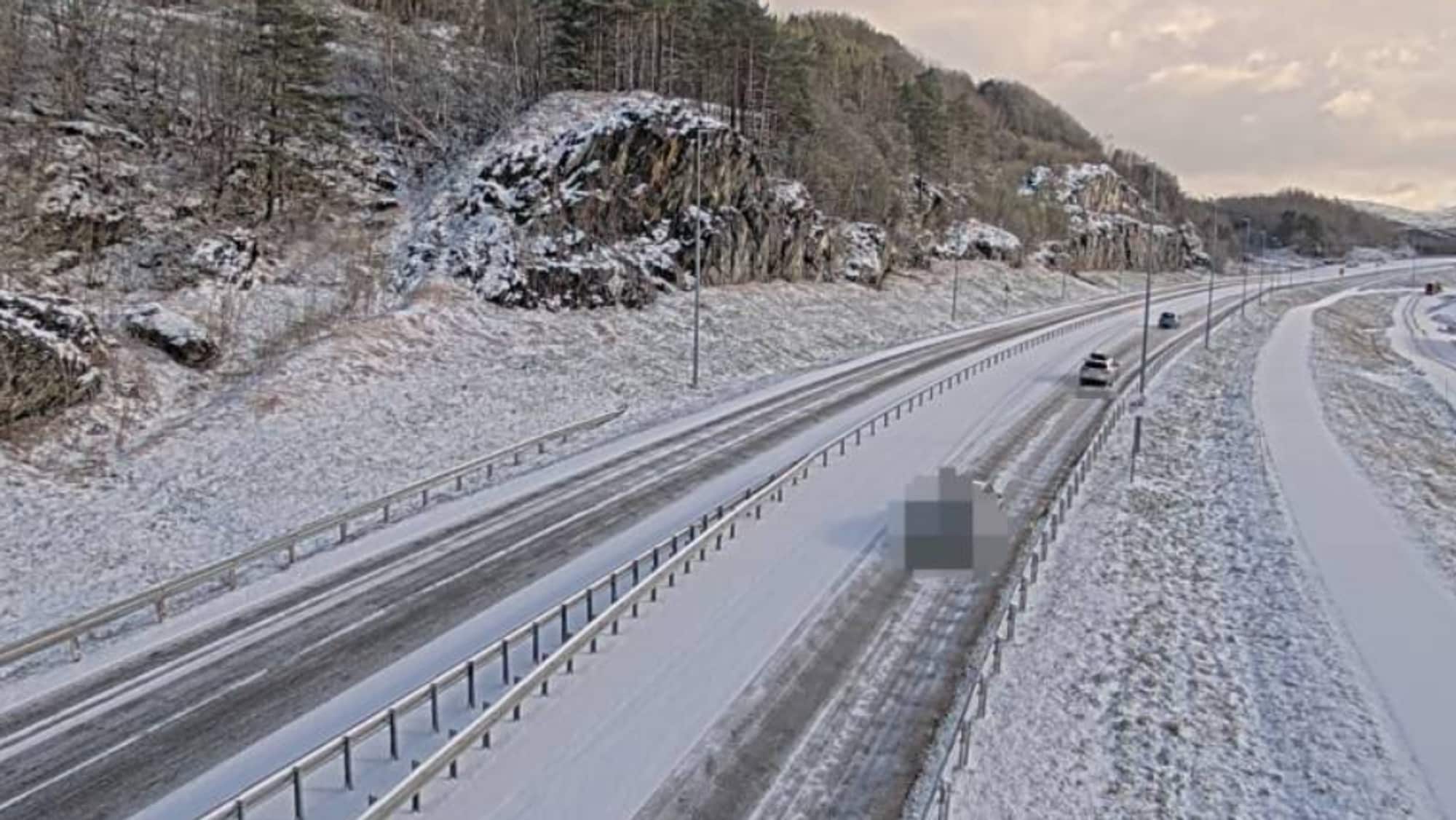Snødekt vei med biler som kjører på. 