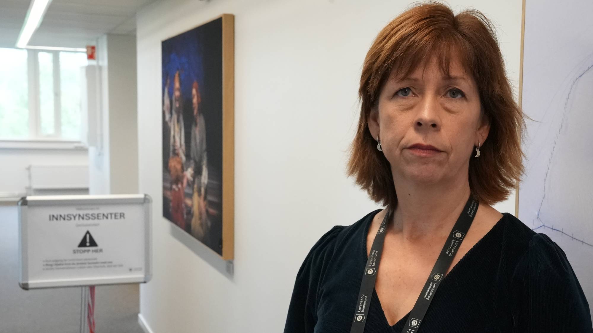 Alvorlig dame foran skilt hvor det står innsynssenter 