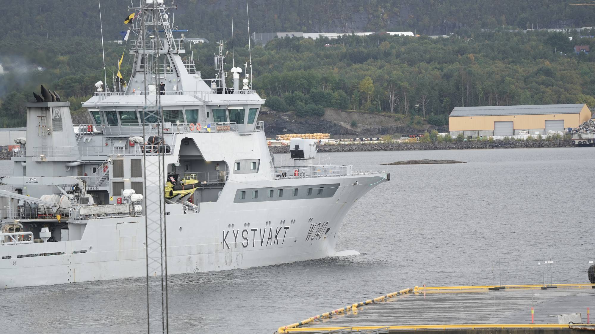 Kystvaktfartøyet KV Sortland W340 seiler på vannet nær en kai. (Bildebeskrivelsen er laget av en KI-tjeneste)