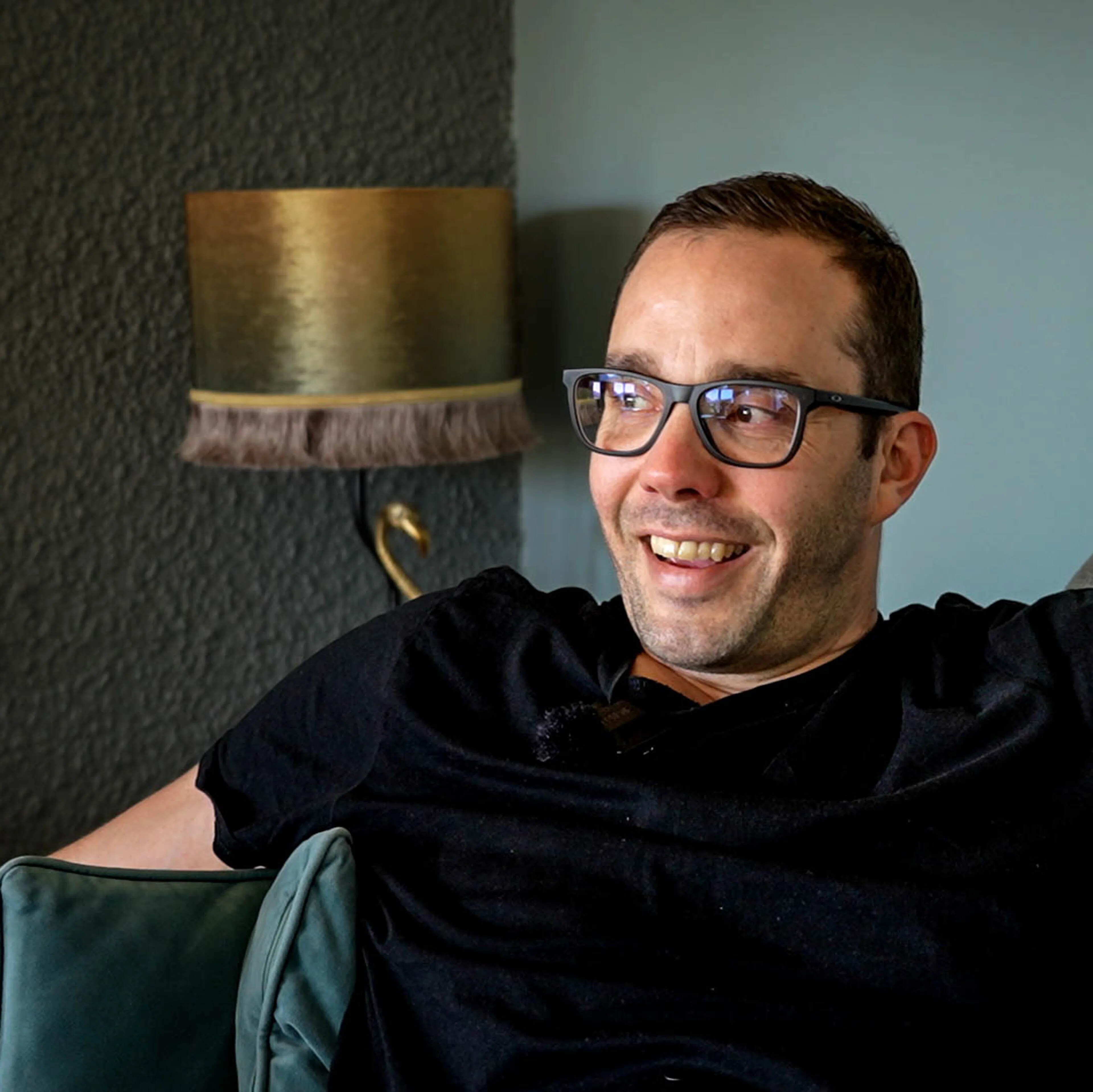 Mann sitter i sofaen og forteller