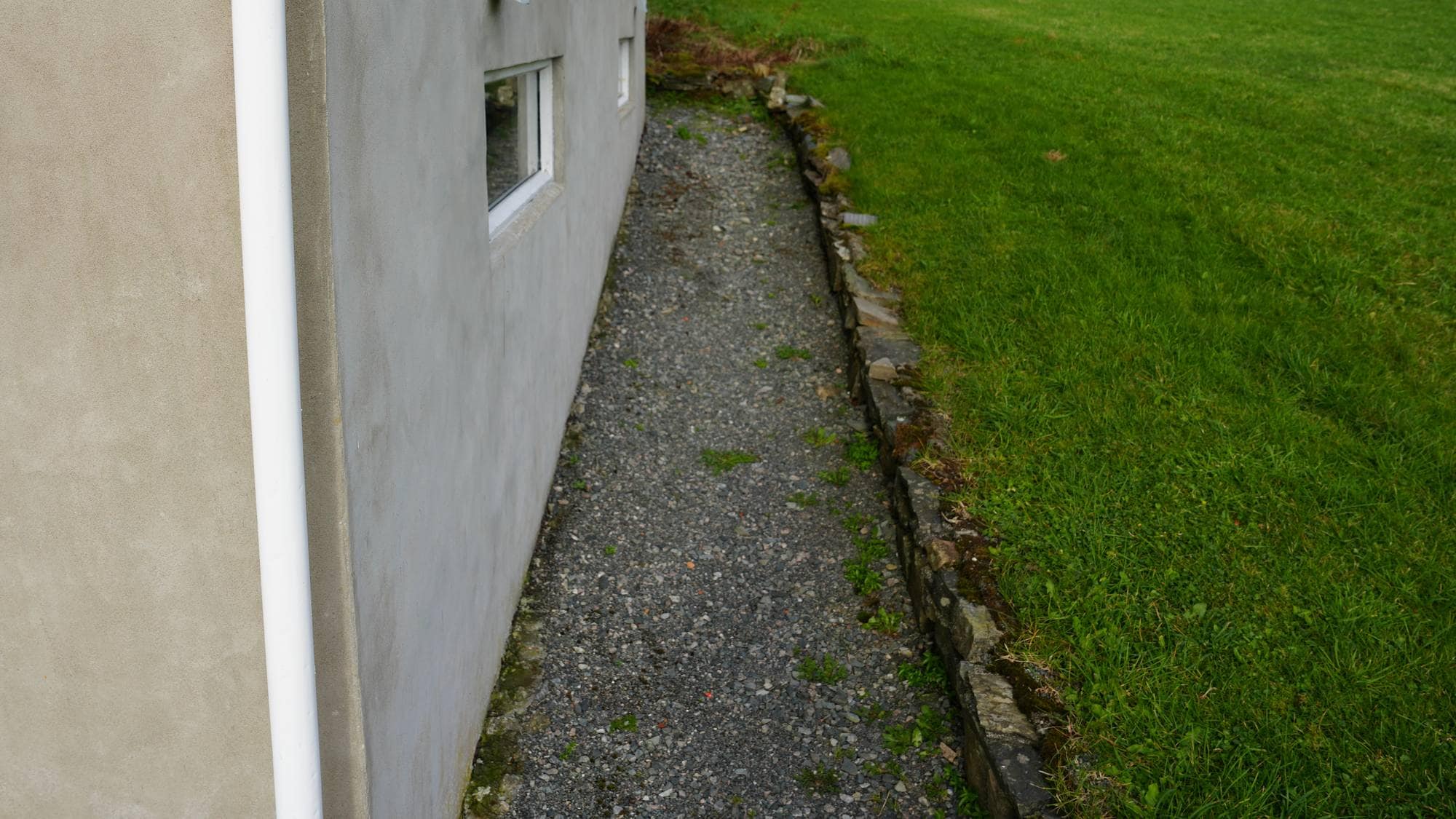 Maskert og valdeleg innbrot i ein bustad i Fana i Bergen: Plenen, grusvegen og grunnmuren til det aktuelle huset.