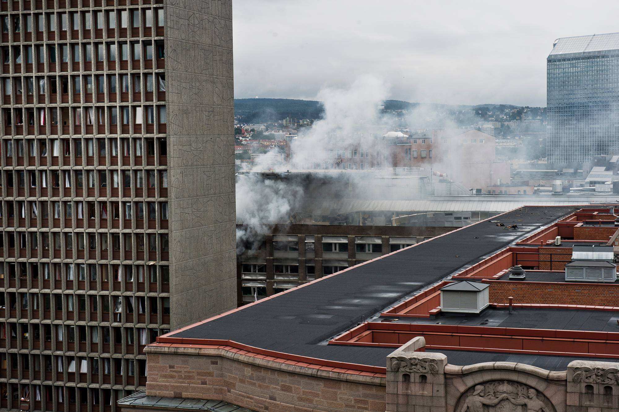 Røyk stiger opp fra regjeringskvartalet i Oslo etter bombeangrepet 22. juli 2011. (Bildebeskrivelsen er laget av en KI-tjeneste)