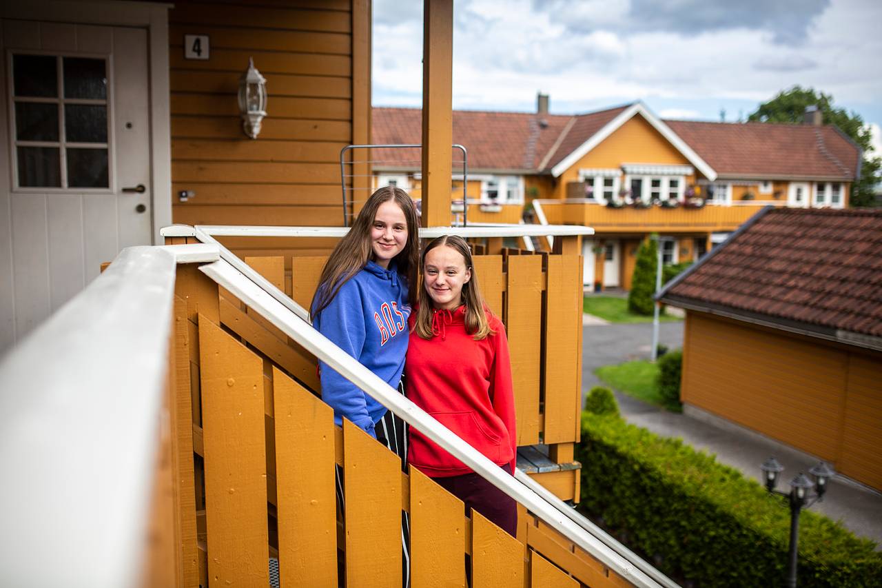 To jenter står i en trapp blant gule hus.