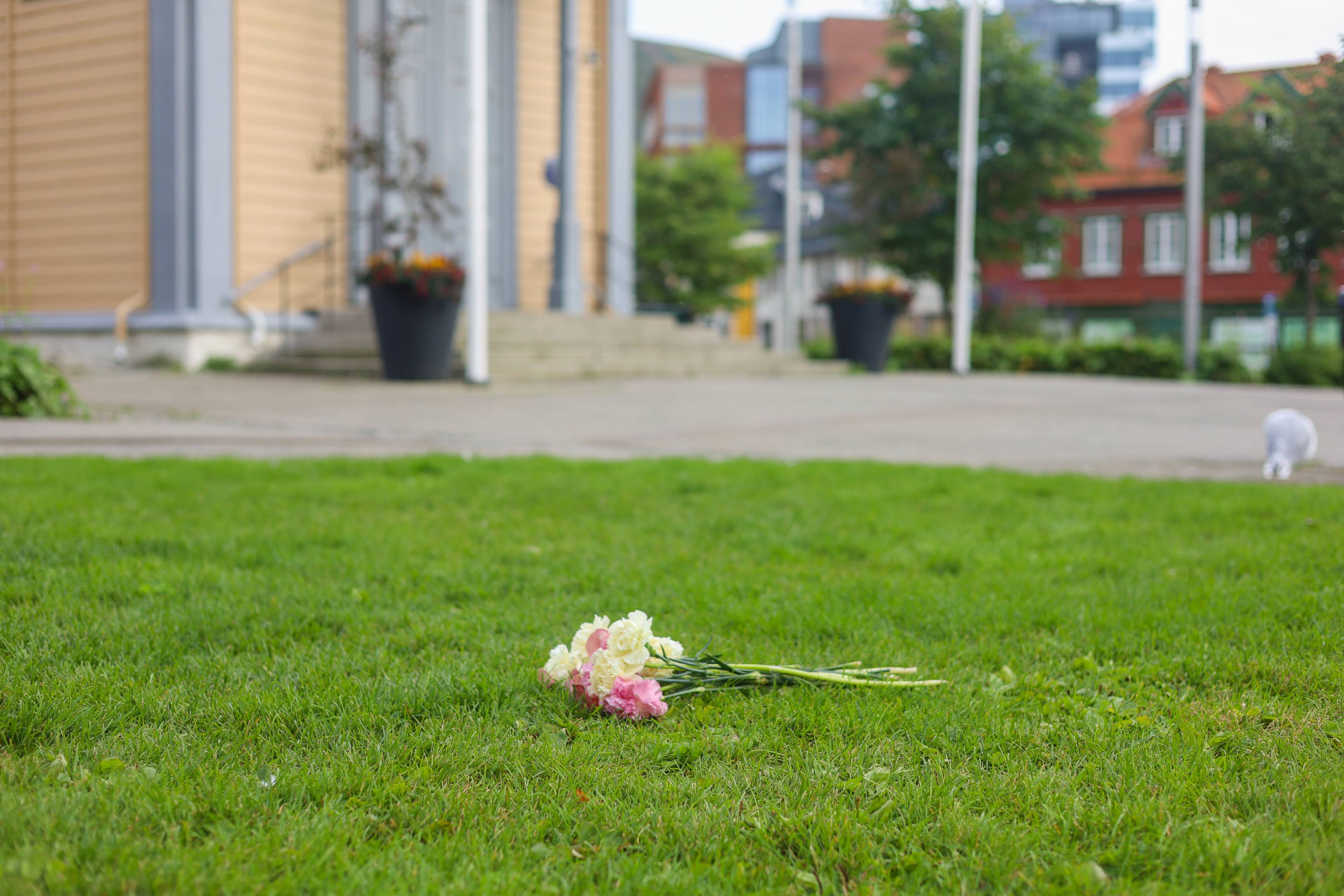 En enslig blomsterbukett med hvite og rosa blomster ligger på en gressplen.