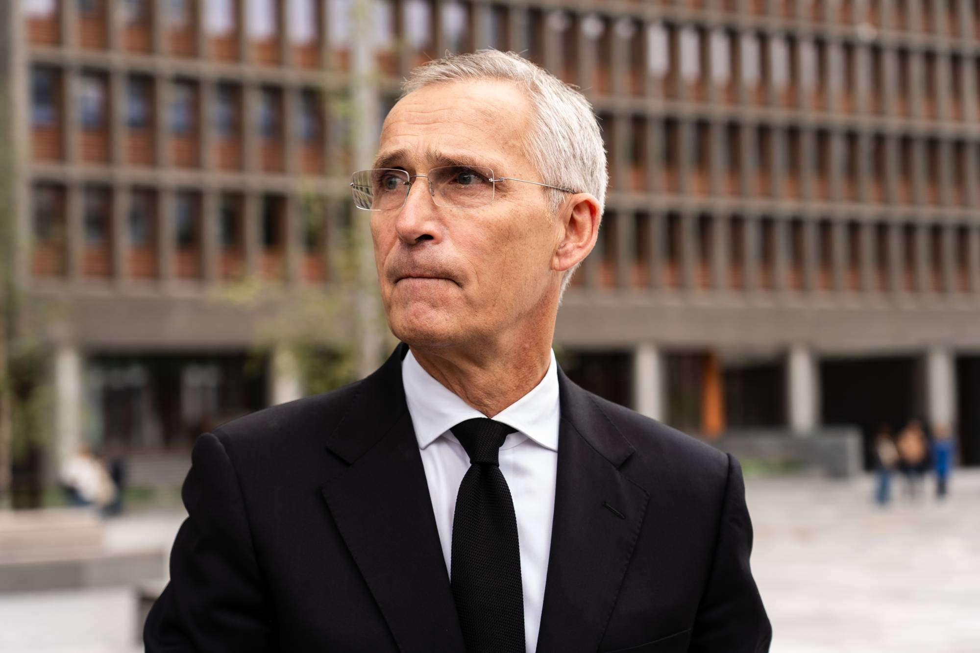 Bildet viser en mann med et bekymret ansiktsuttrykk foran et kontorbygg.