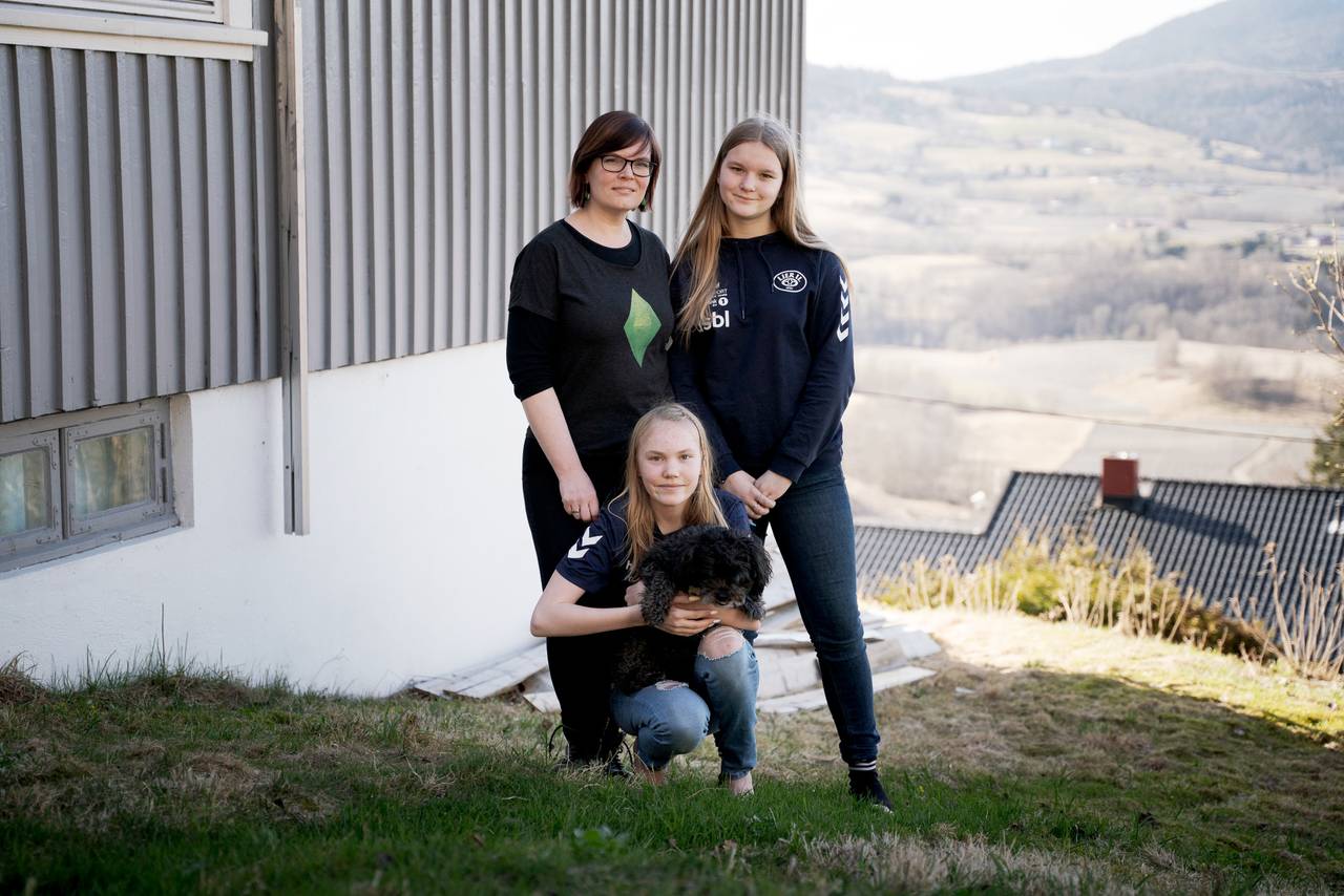 Mamma Maren og døtrene Anna og Nora Søfting Redalen i hagen foran huset sitt. Hunden Kavring på fanget til Nora.