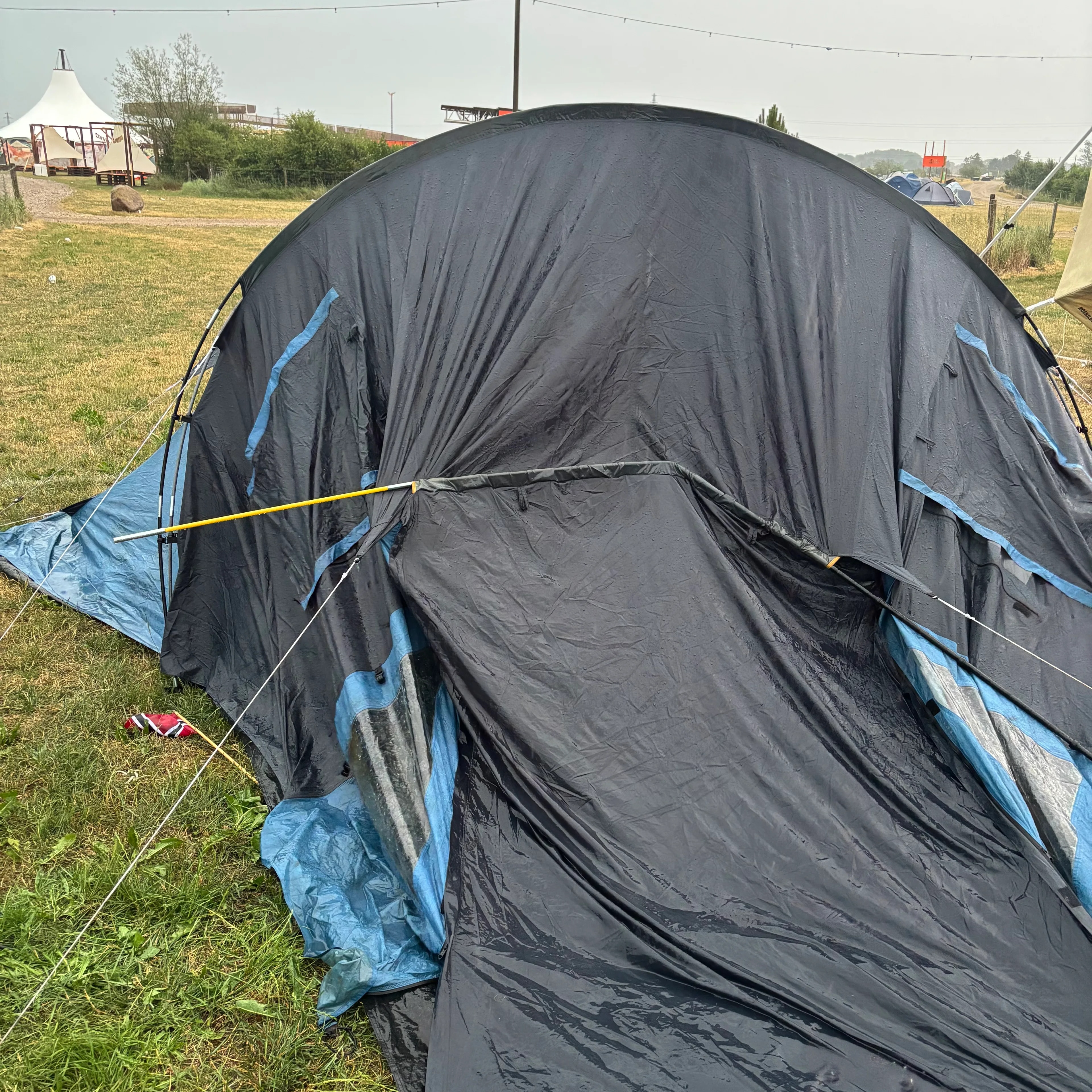 Et sammenfalt telt står på et gressfelt ved en campingplass. (Bildebeskrivelsen er laget av en KI-tjeneste)