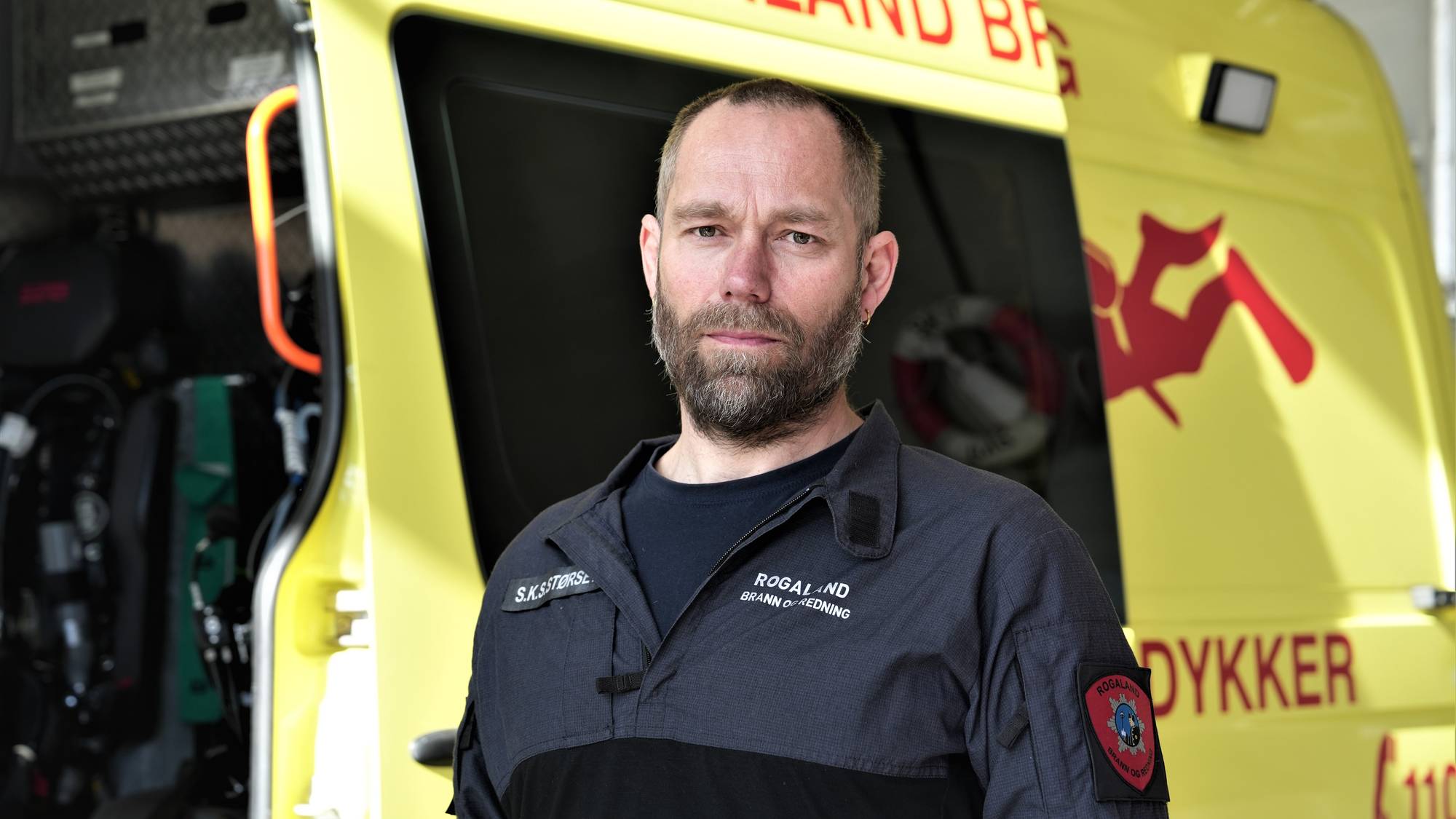 Brannkonstabel i sort uniform fremfor en brannbil.
