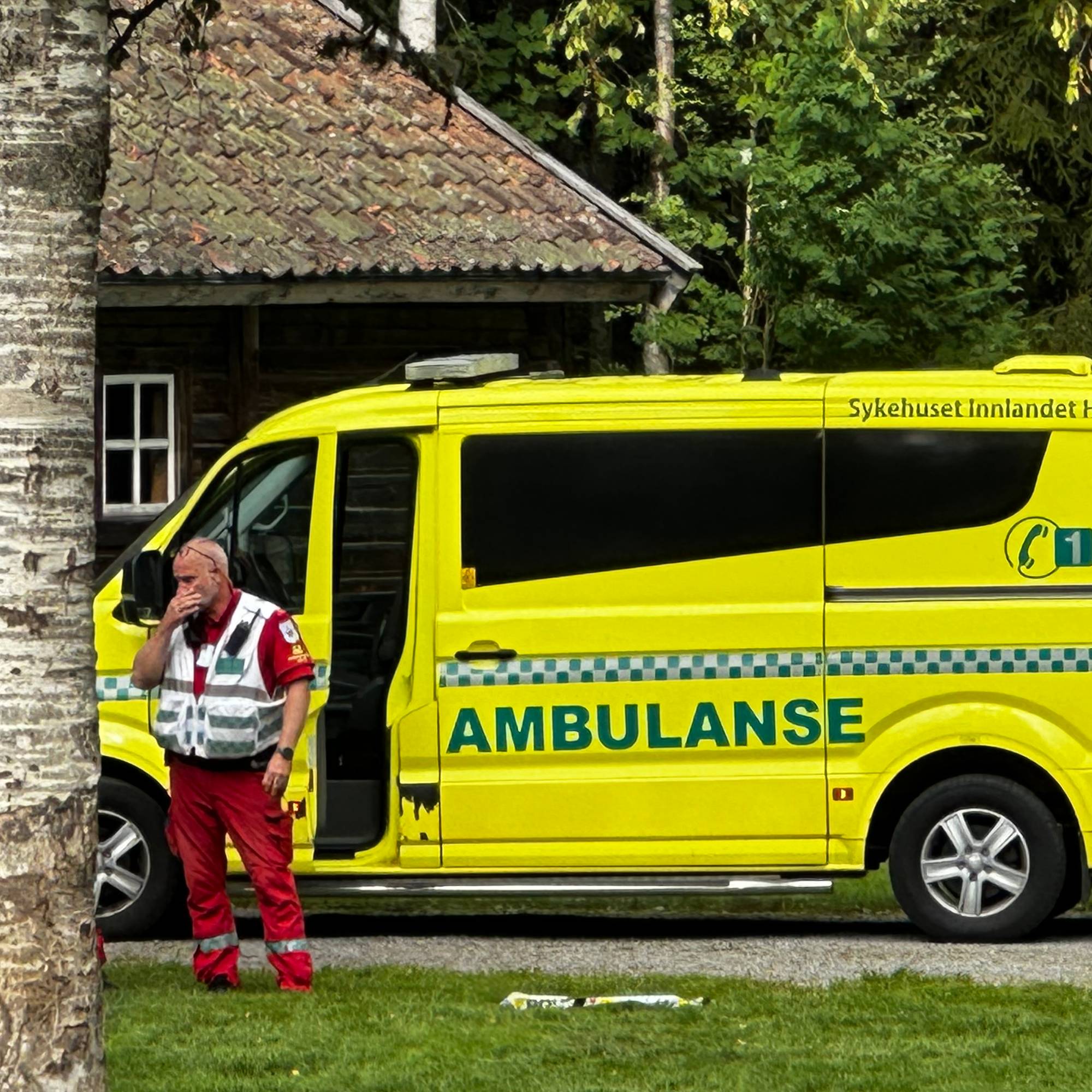 Ambulansepersonell og politi ved en ambulanse i et skogsområde.