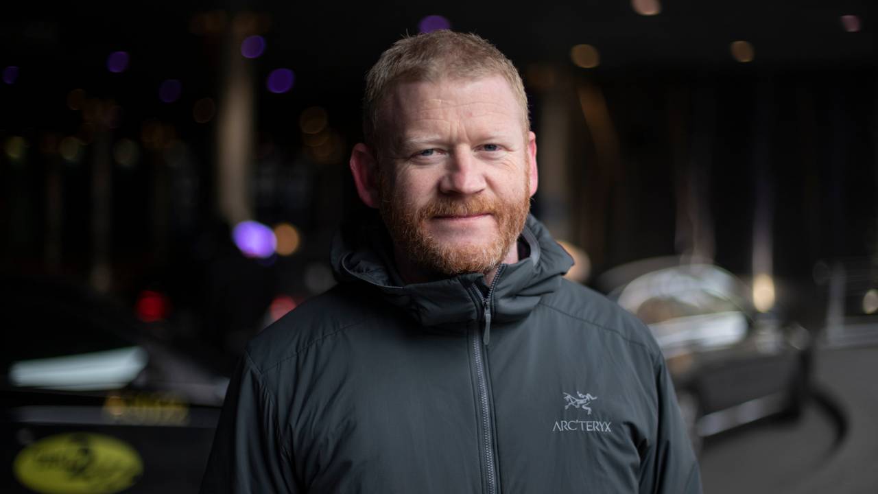 Tommy Henriksen er daglig leder ved Førerhundskolen, som hører inn under Norges blindeforbund. Han står i svart jakke foran taxier på en holdeplass i Oslo sentrum.