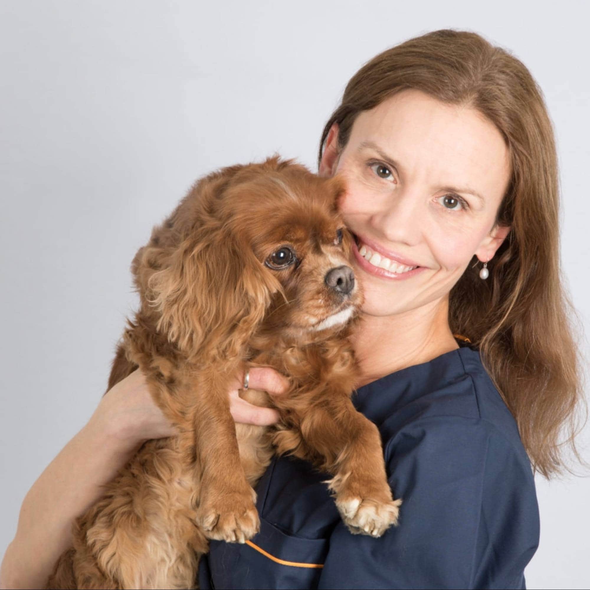 Veterinær i Tromsø. Kvinne i uniform som holder opp en hund. 