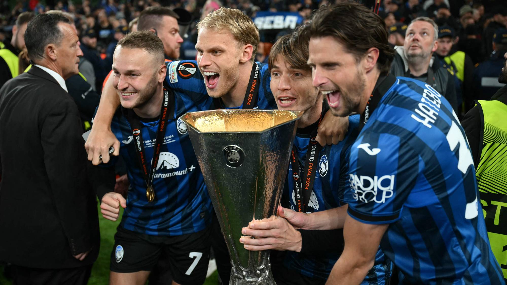 Atalanta-spillere feirer seieren i Europaligaen med trofeet på banen. (Bildebeskrivelsen er laget av en KI-tjeneste)