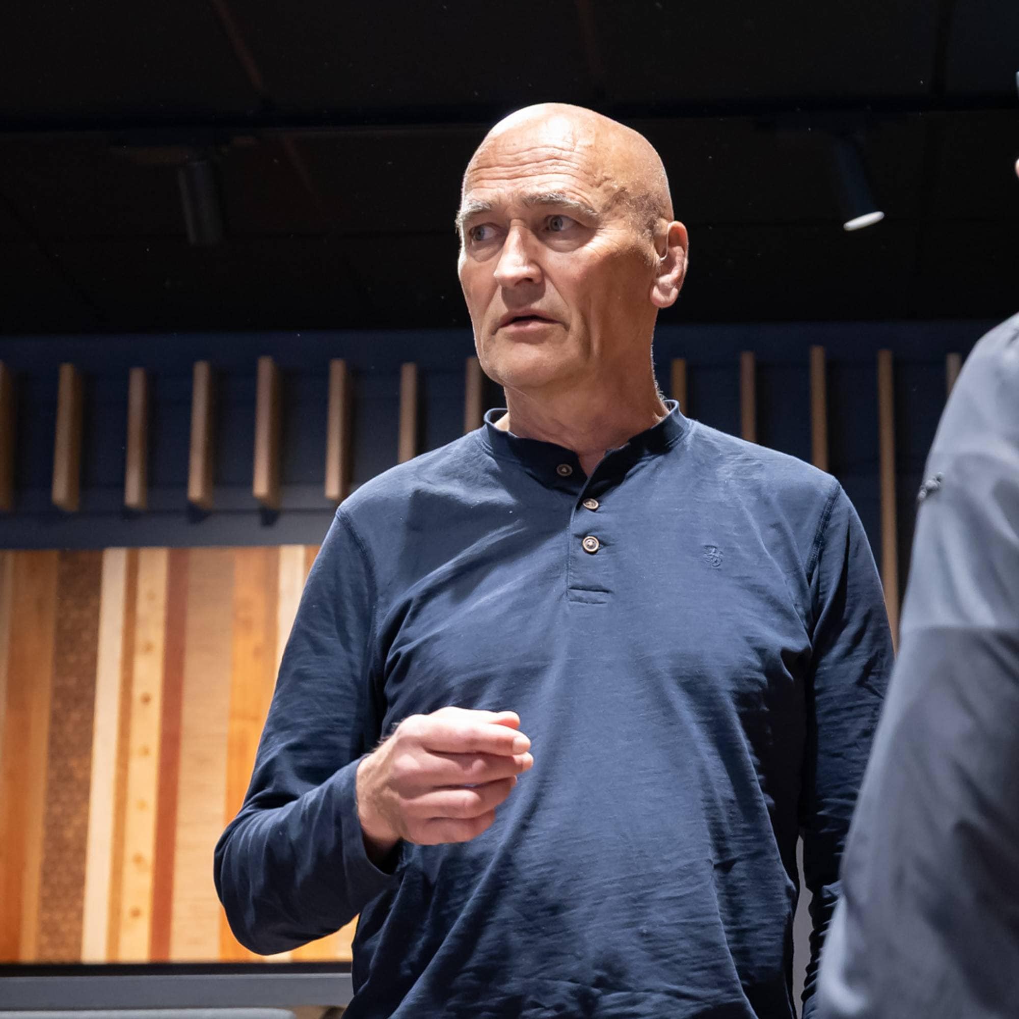 Harry Arne Solberg står i et auditorium. Han snakker med en person som vi kun ser deler av ansiktet til.