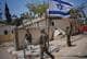 Ohad Zwigenberg / AP,NTB en gruppe soldater som står utenfor en delvis ødelagt bygning, et israelsk flagg veiver i vinden